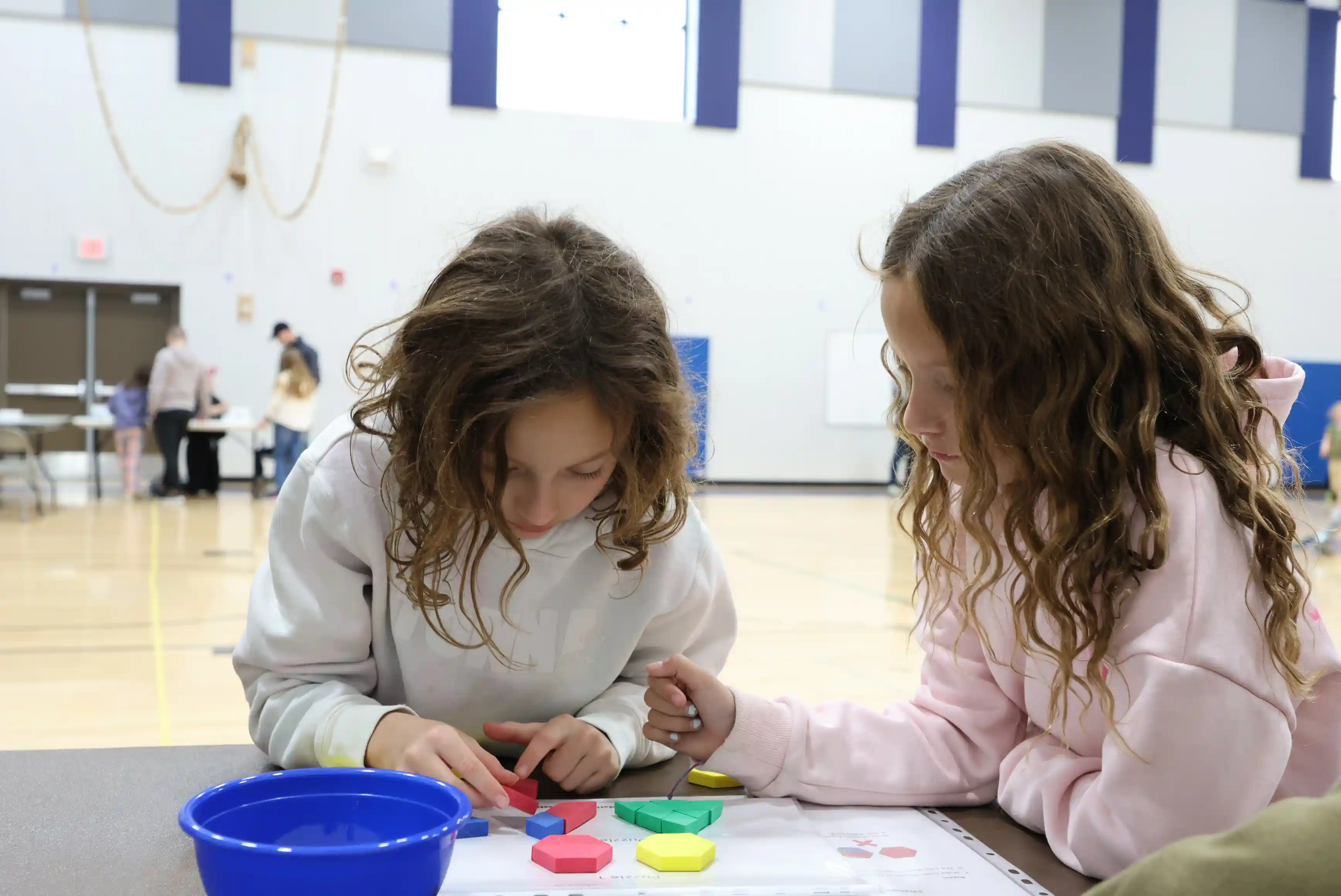 Two students working together to make shapes to create a bigger shape