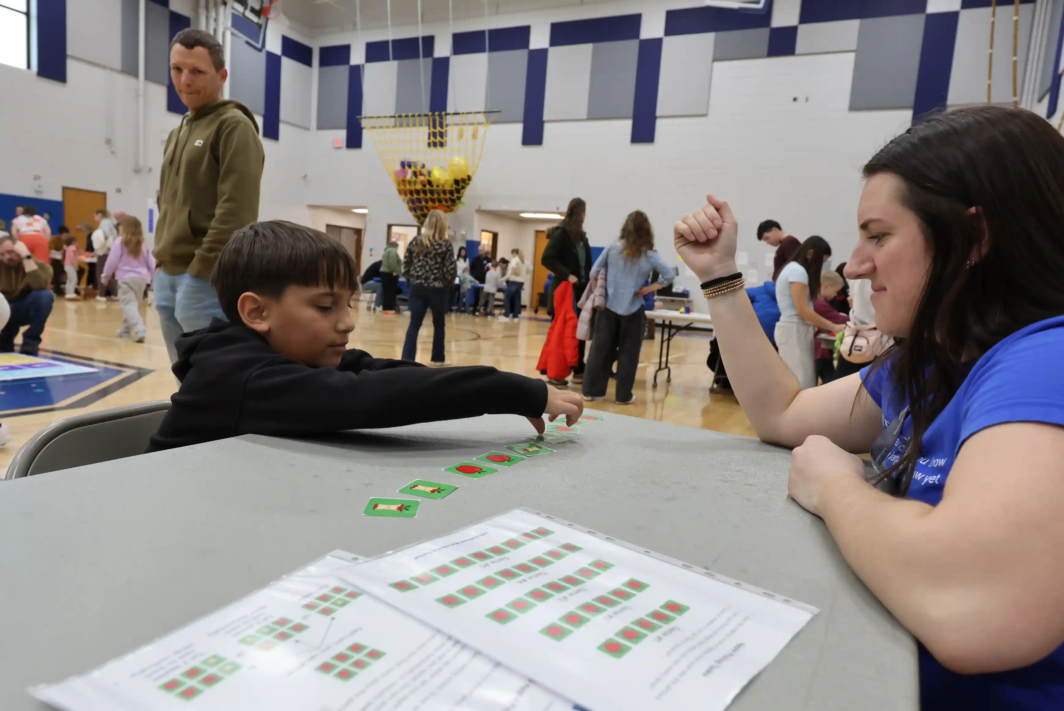 Student and a volunteer playing a game with apples on cards