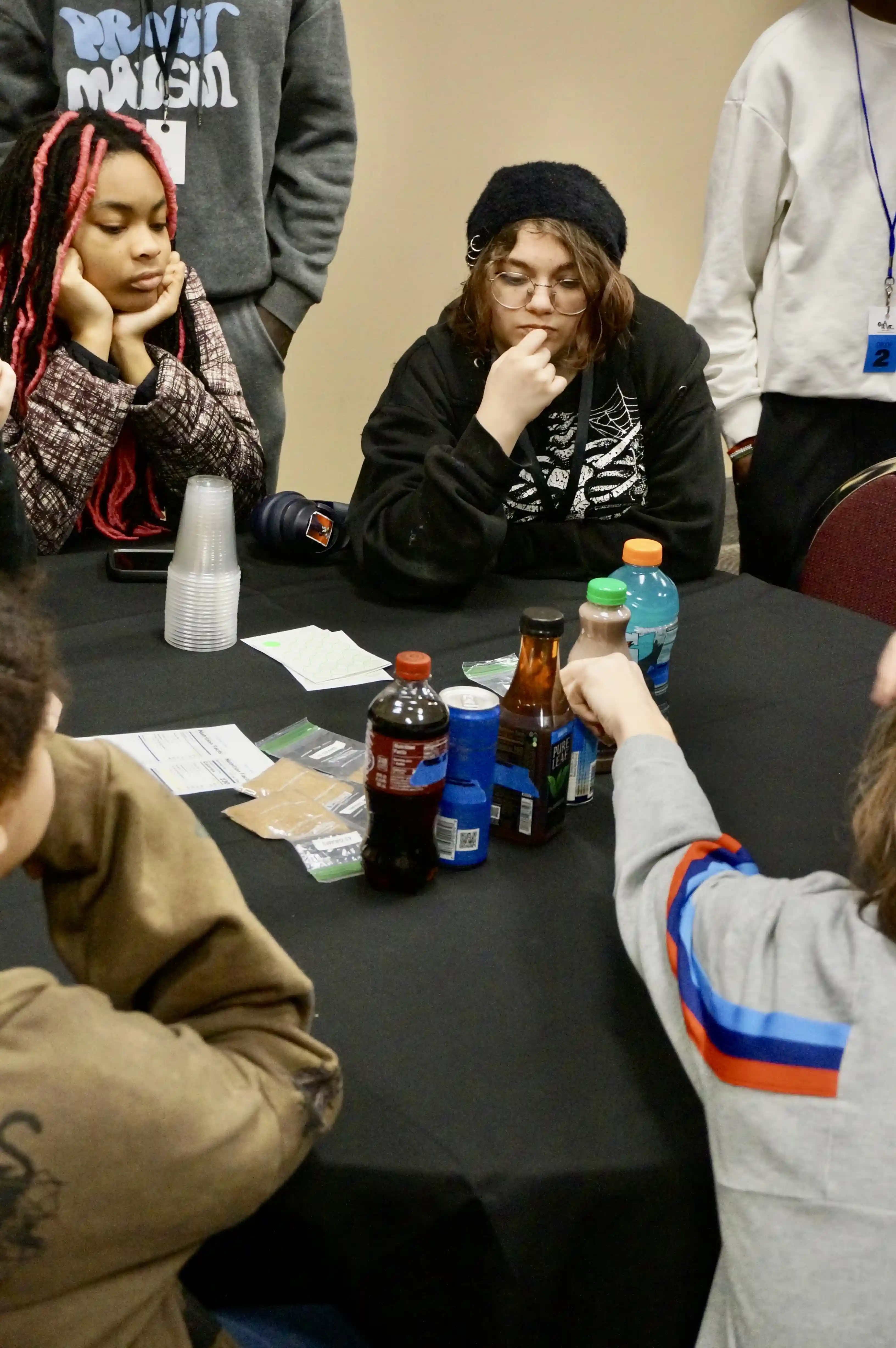 Group of students sitting at a table looking at different drinks