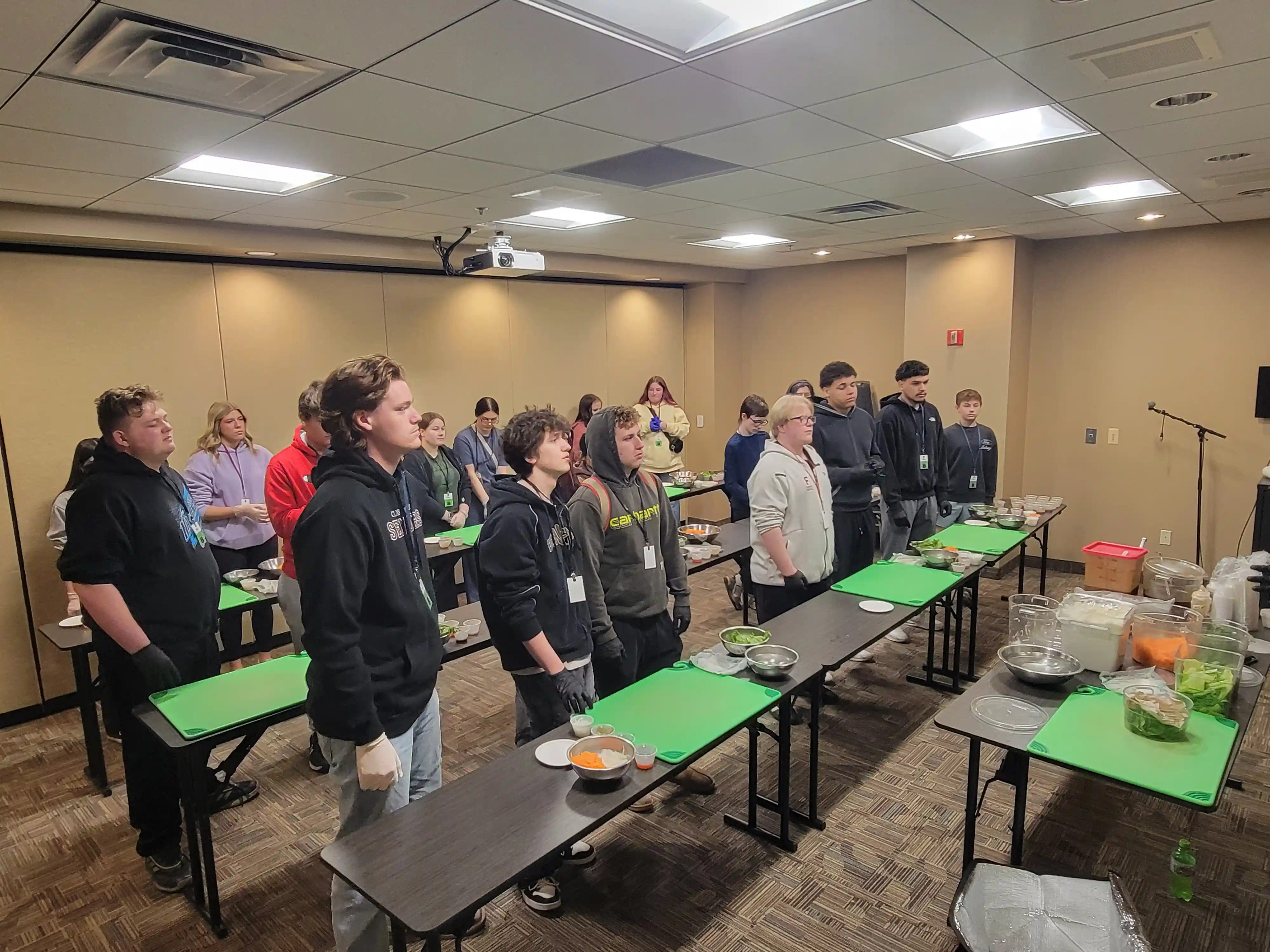 students standing at rows of tables with cutting boards