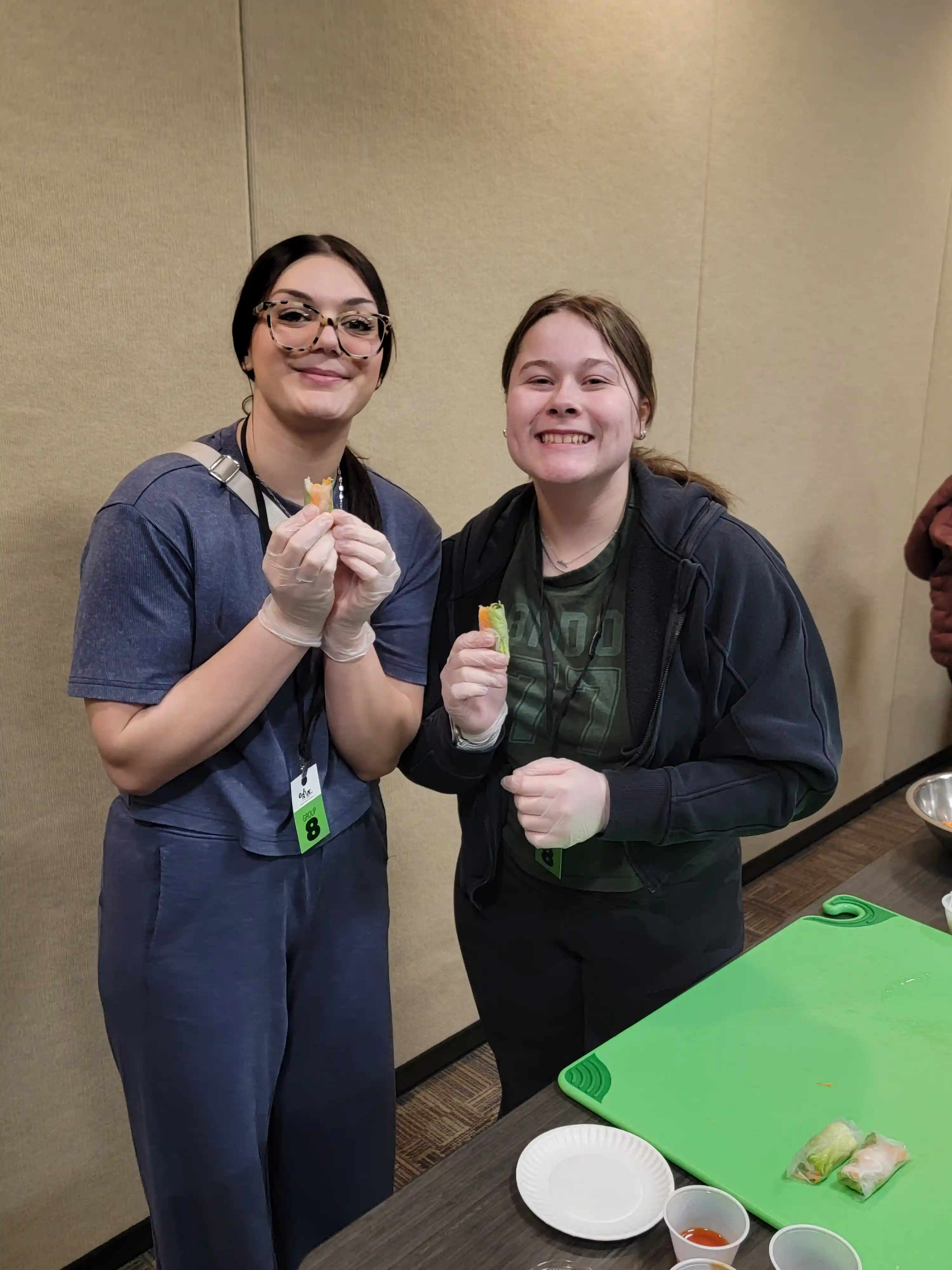students at tables preparing food and smiling