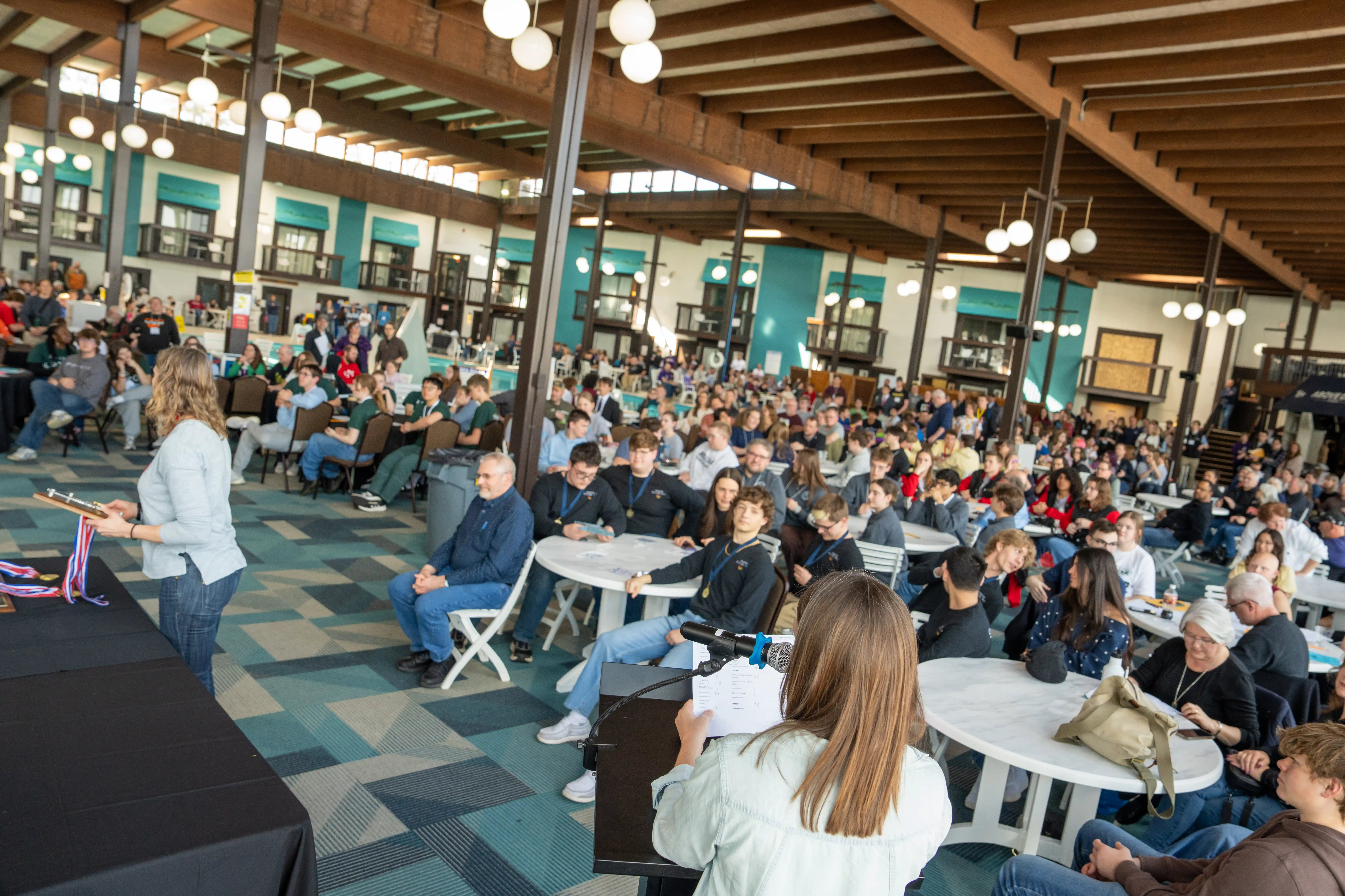 Students and adults in a big room sitting at tables