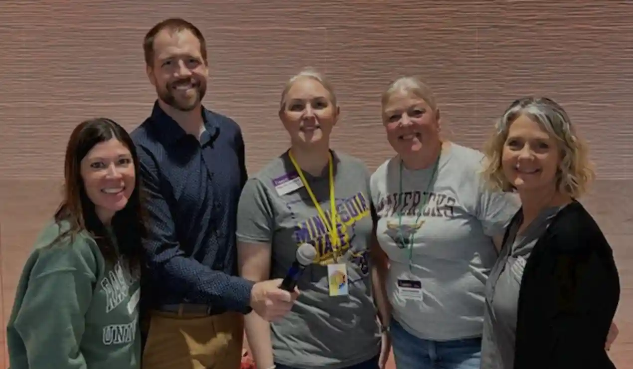 group of 5 adults standing in a group smiling
