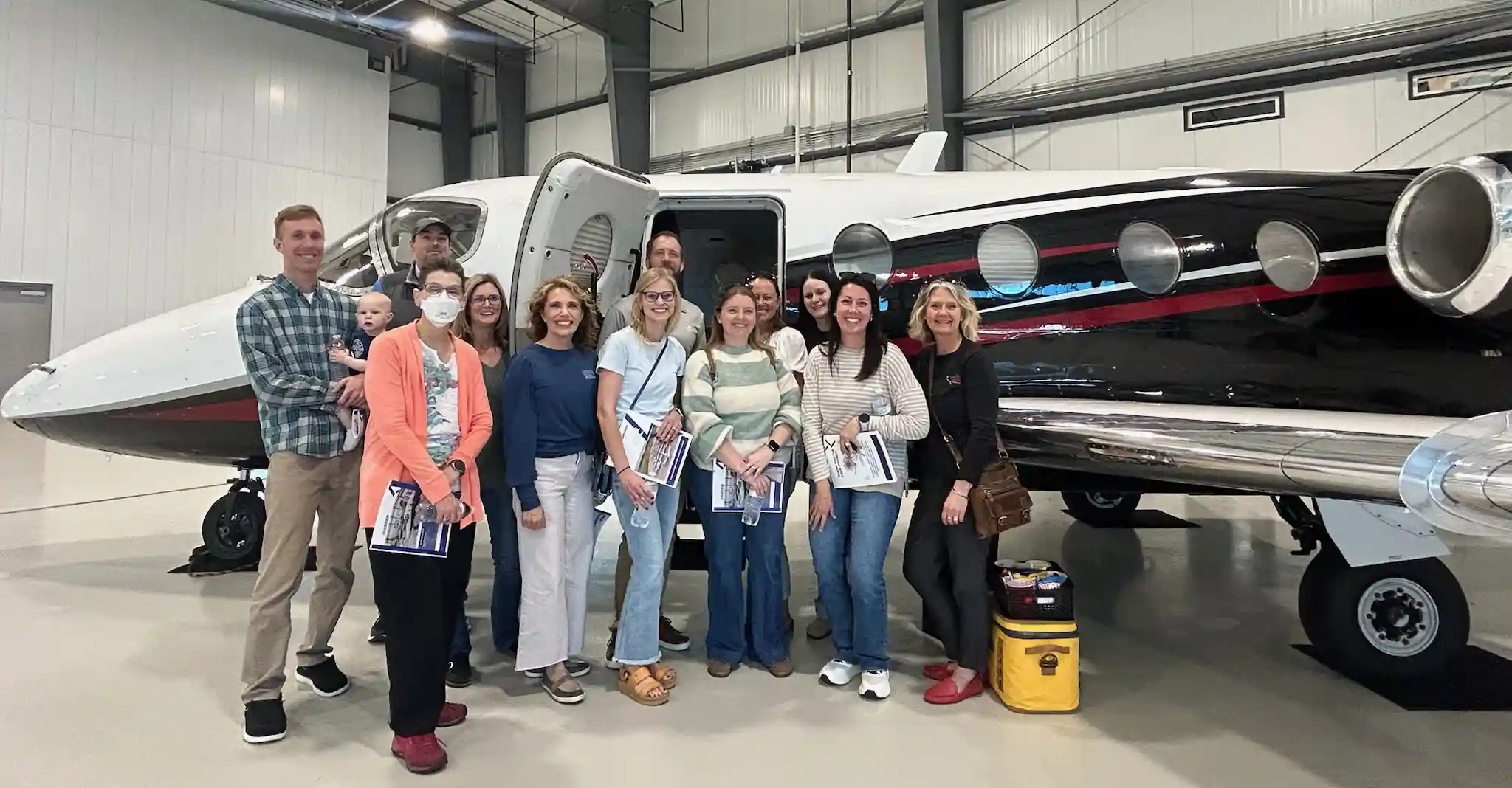 A group of people posing for a photo in front of a small plane