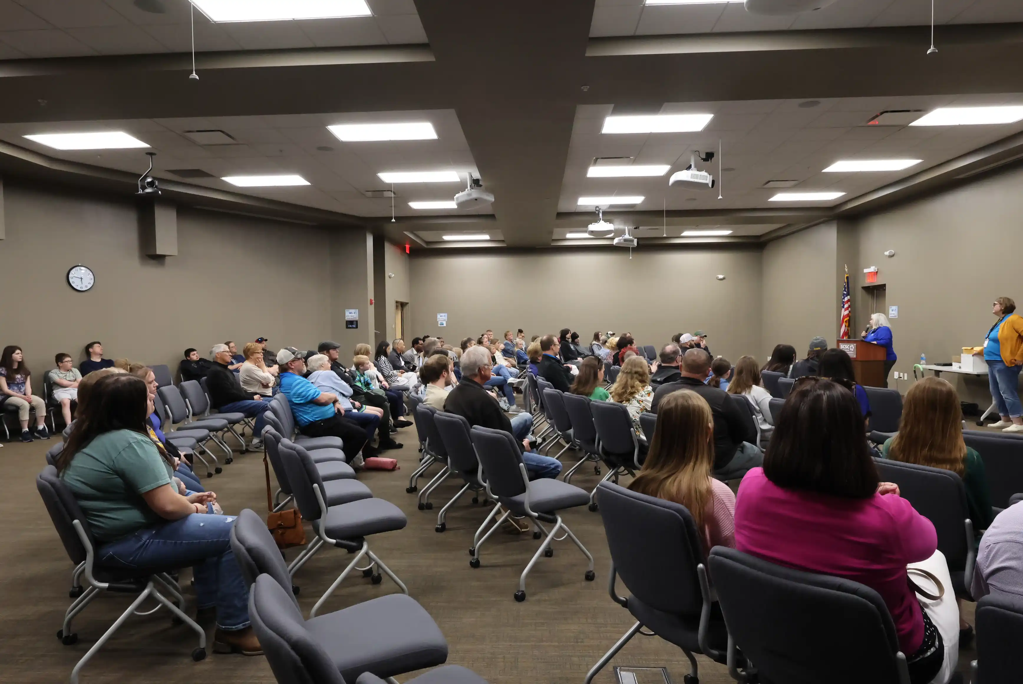 people sitting in chairs listening to students present