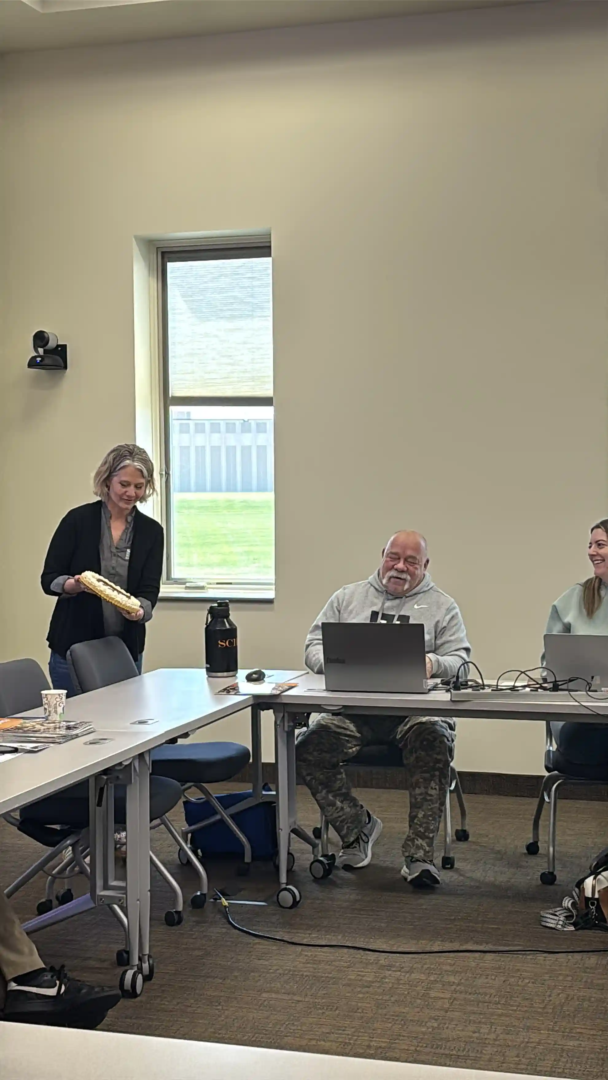 Gwenn holding a cake and presenting it to Educator Steve Schlager