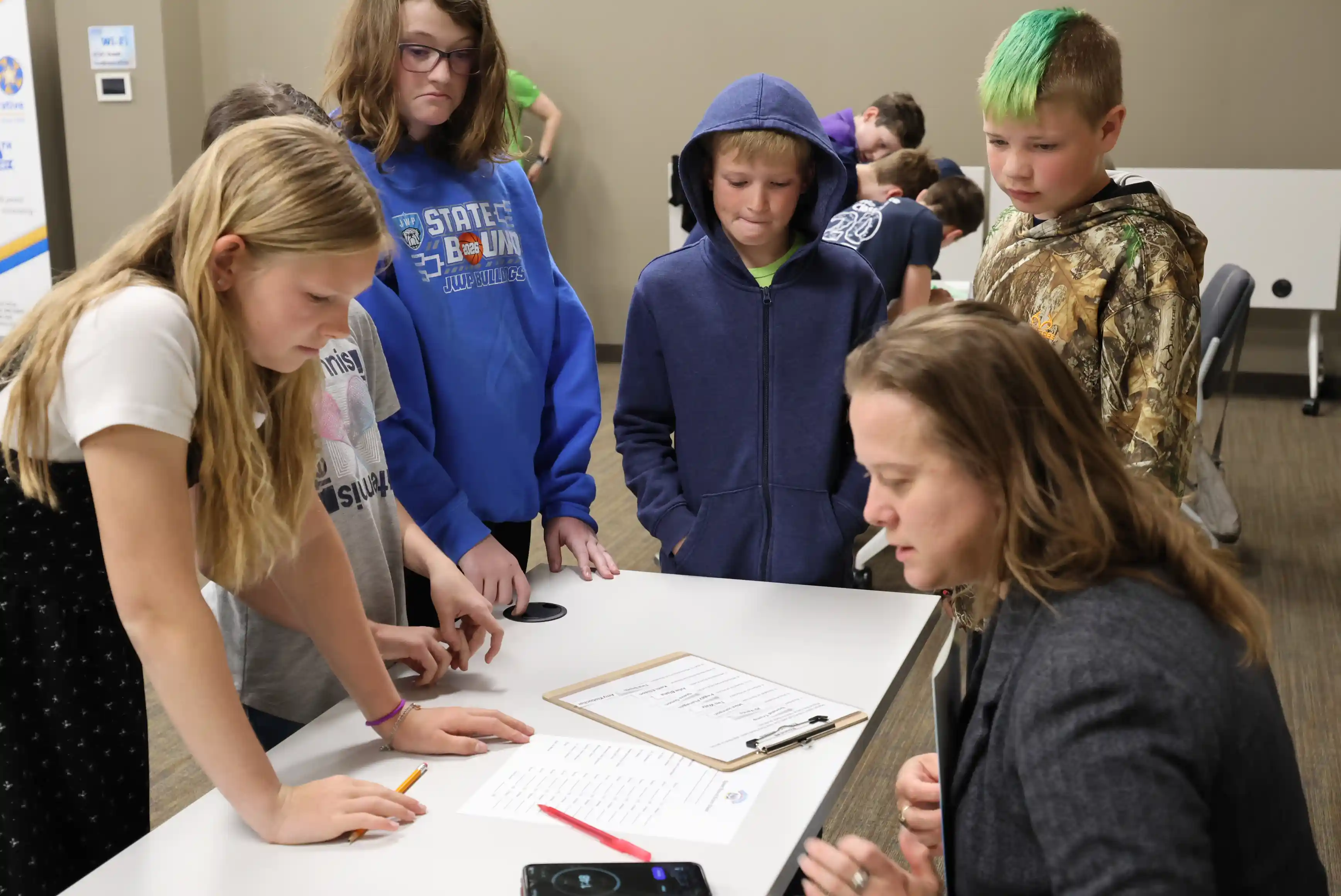 students working together around a table with an adult giving instructions