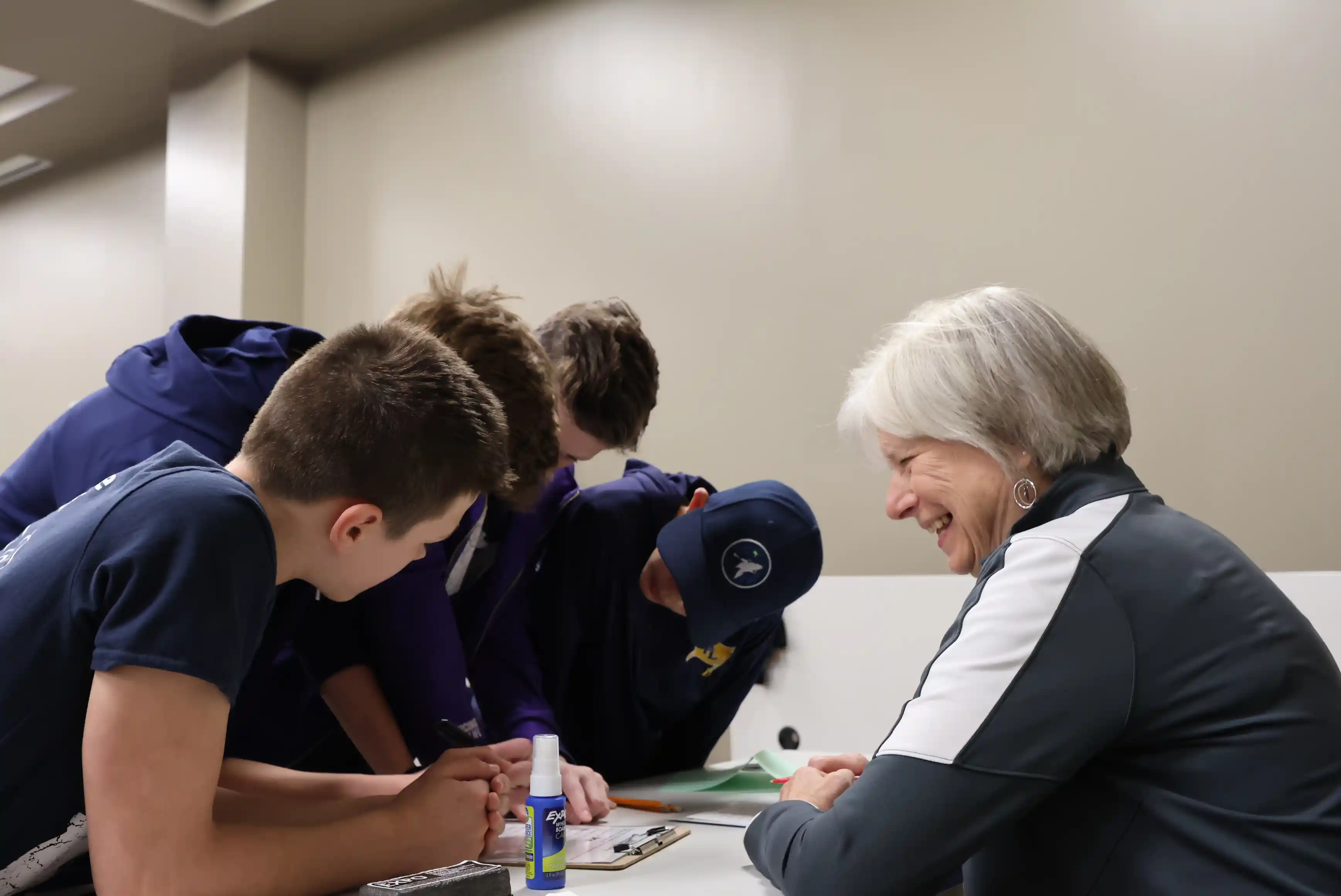 students working together around a table with an adult giving instructions