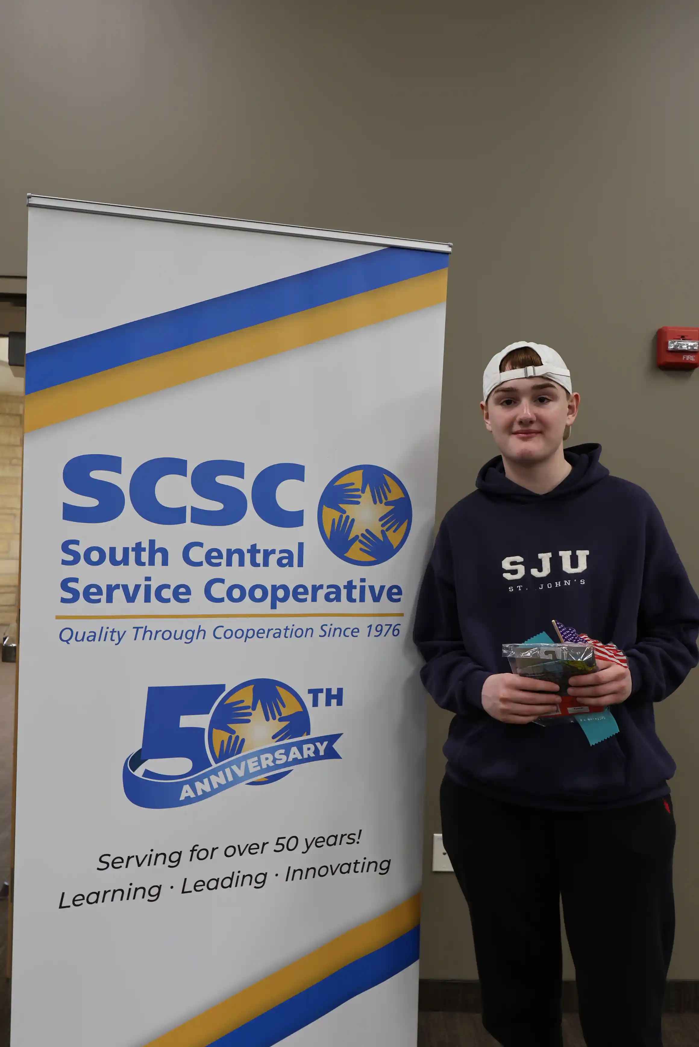 student posing for picture holding a ribbon and winning gifts
