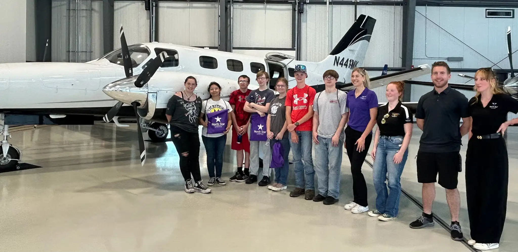students and adults standing by a small airplane