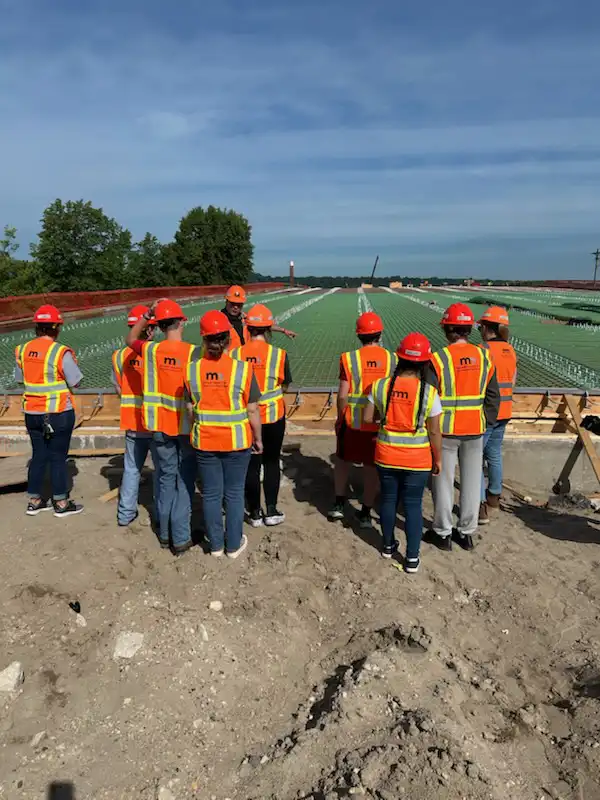 students in hardhats and construction vests at a bridge construction site