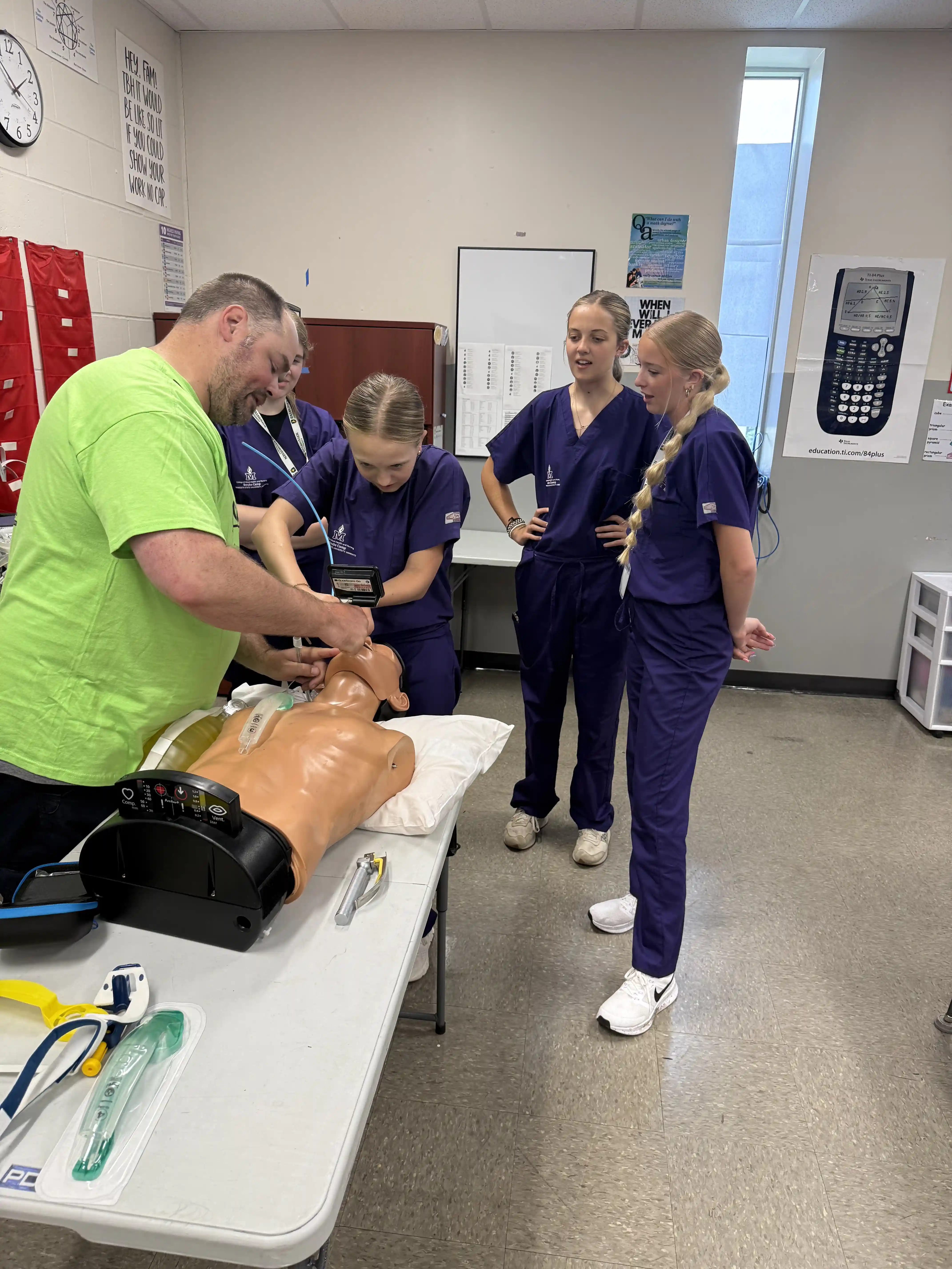 Scrubs Camp students watching an instructor insert a breathing tube into a "dummy" 