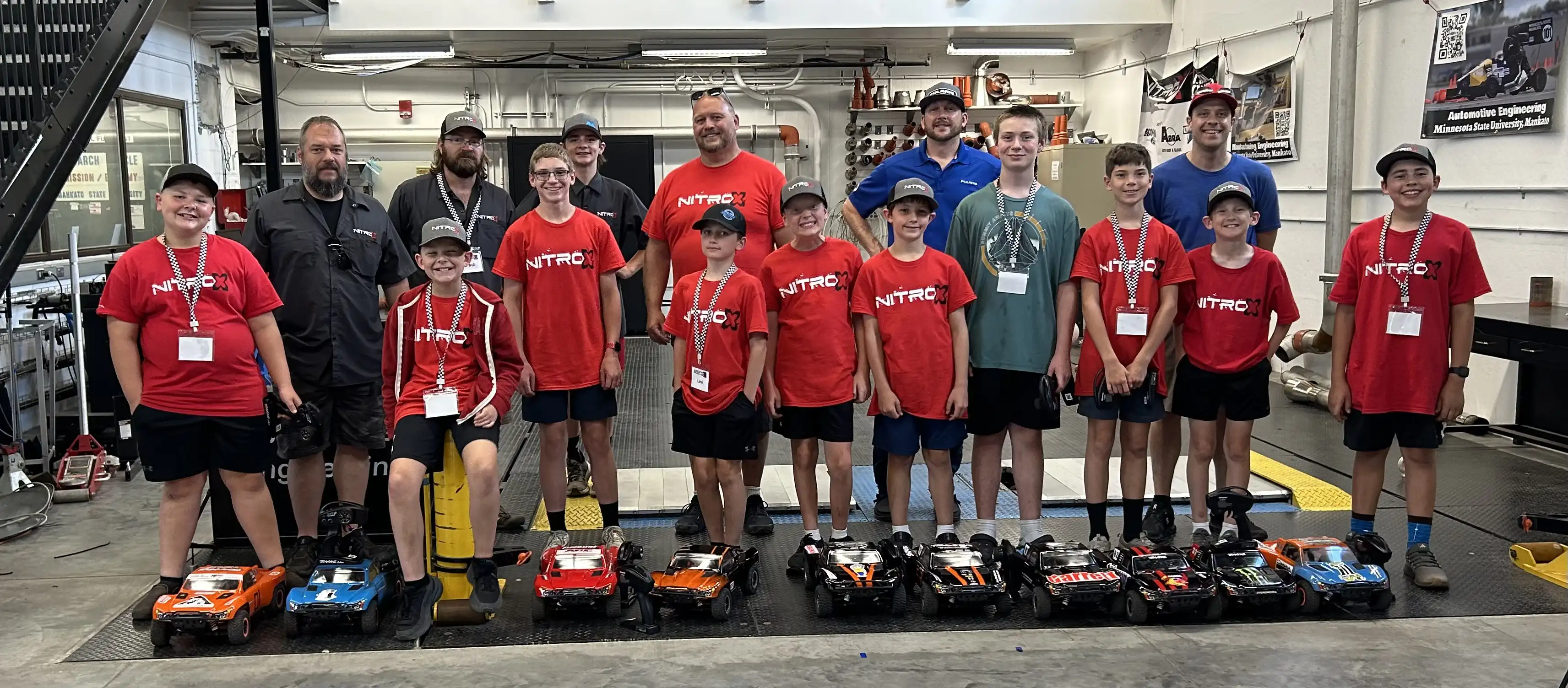 Students posing for a picture with the race cars they built.