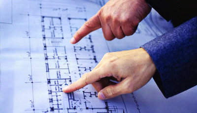Two hands pointing at a blueprint plan with architectural drawings and measurements.
