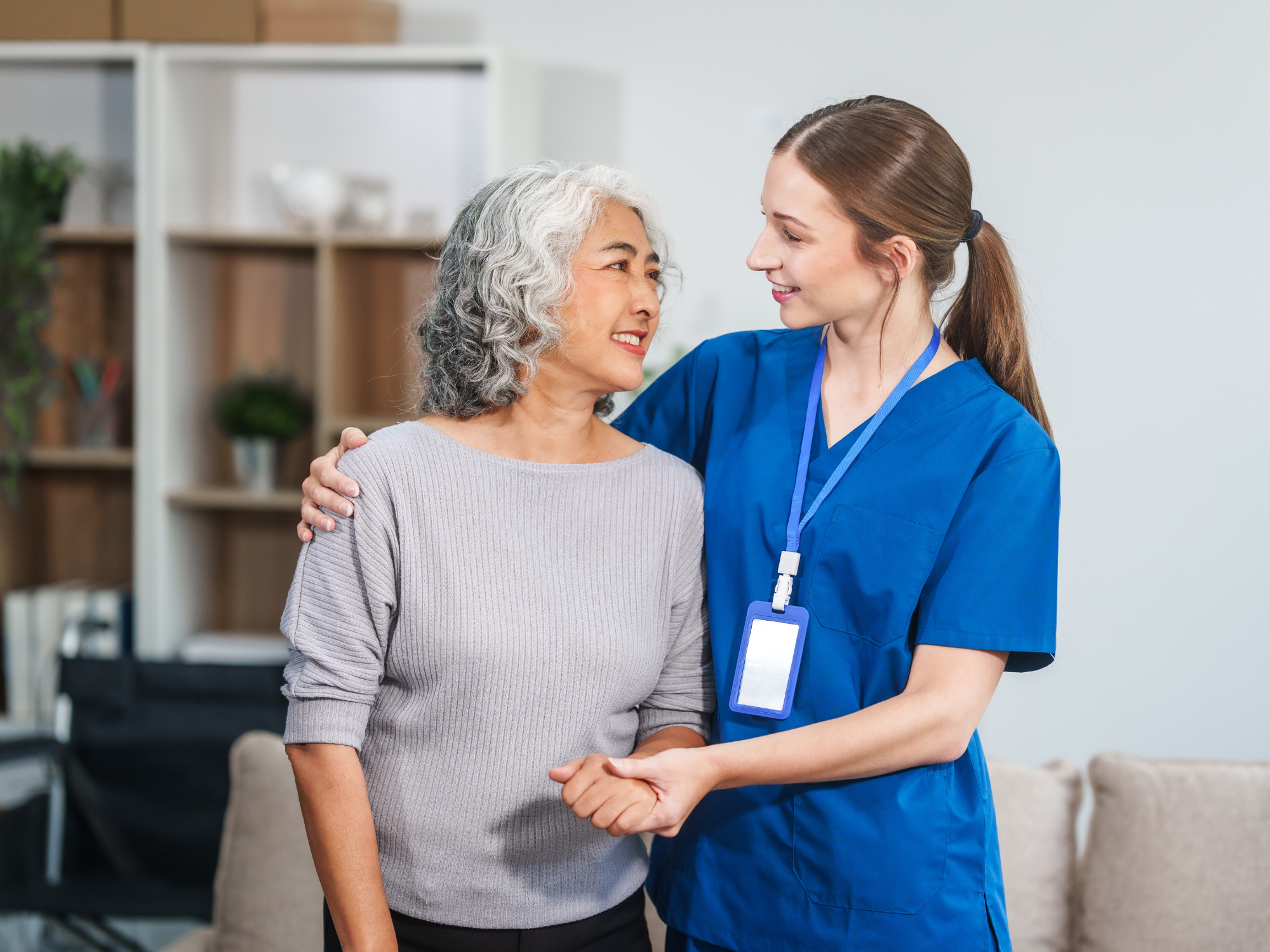 Female healthcare professional measuring the blood pressure of an elderly man seated comfortably on his living room couch.