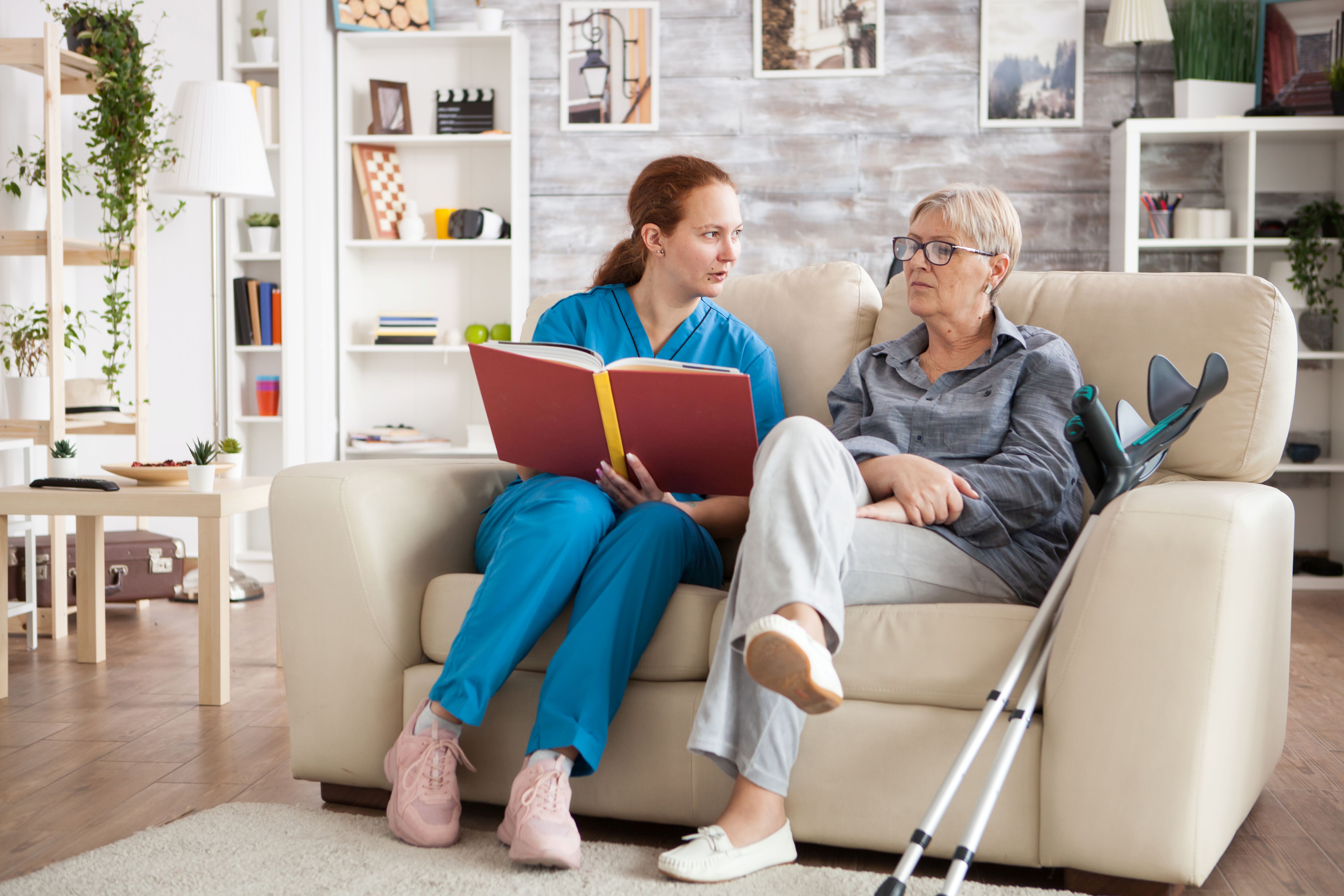 Female nurse reading a book for a senior woman