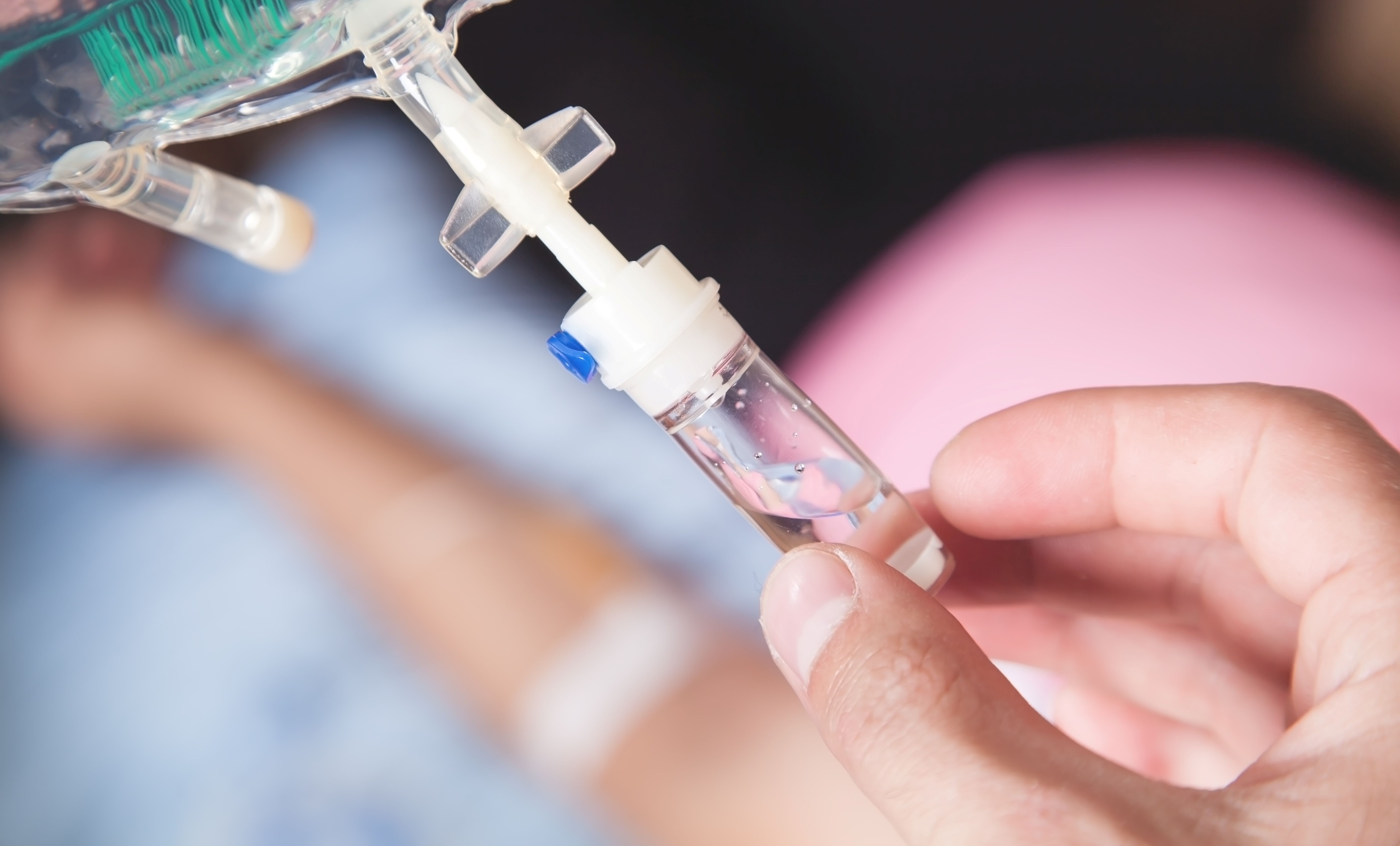 hand connecting an intravenous drip in home.