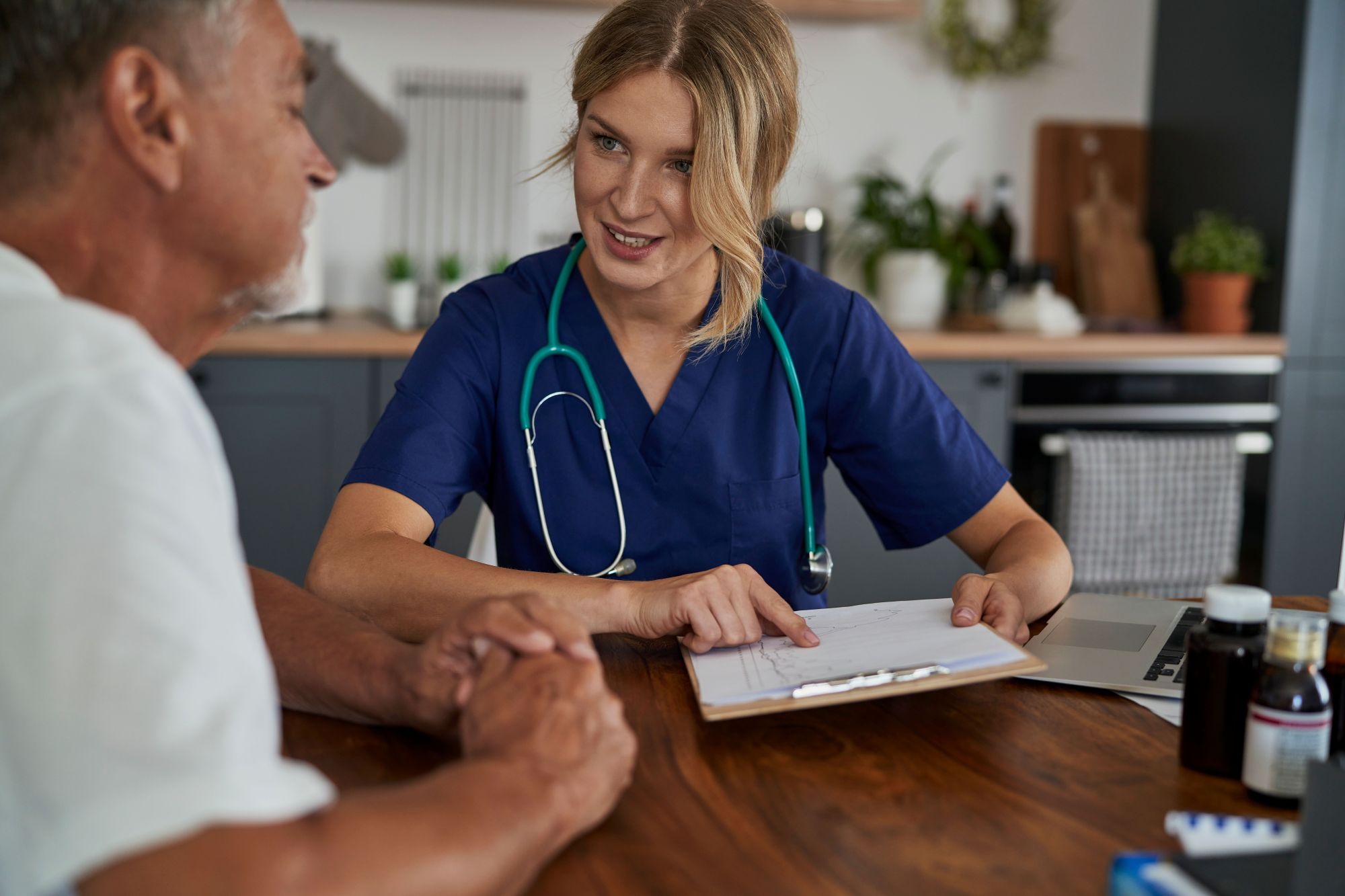Caucasian female home healthcare professional at the home visit conversating with male senior patient