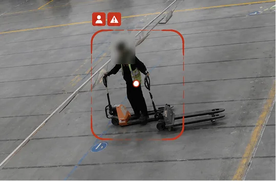 Top-down camera view of a worker with a pallet jack, face blurred