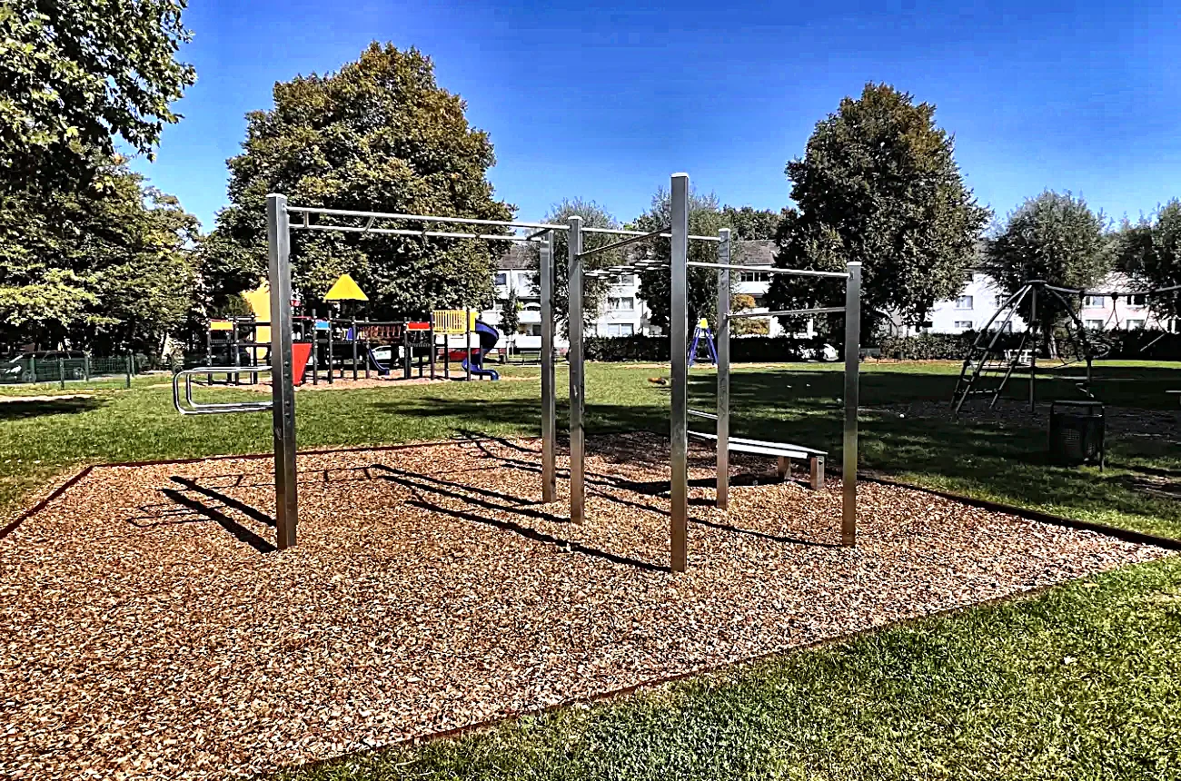 Calisthenics-Anlage mit Stangenkombination und Fallschutzbelag im Grünen