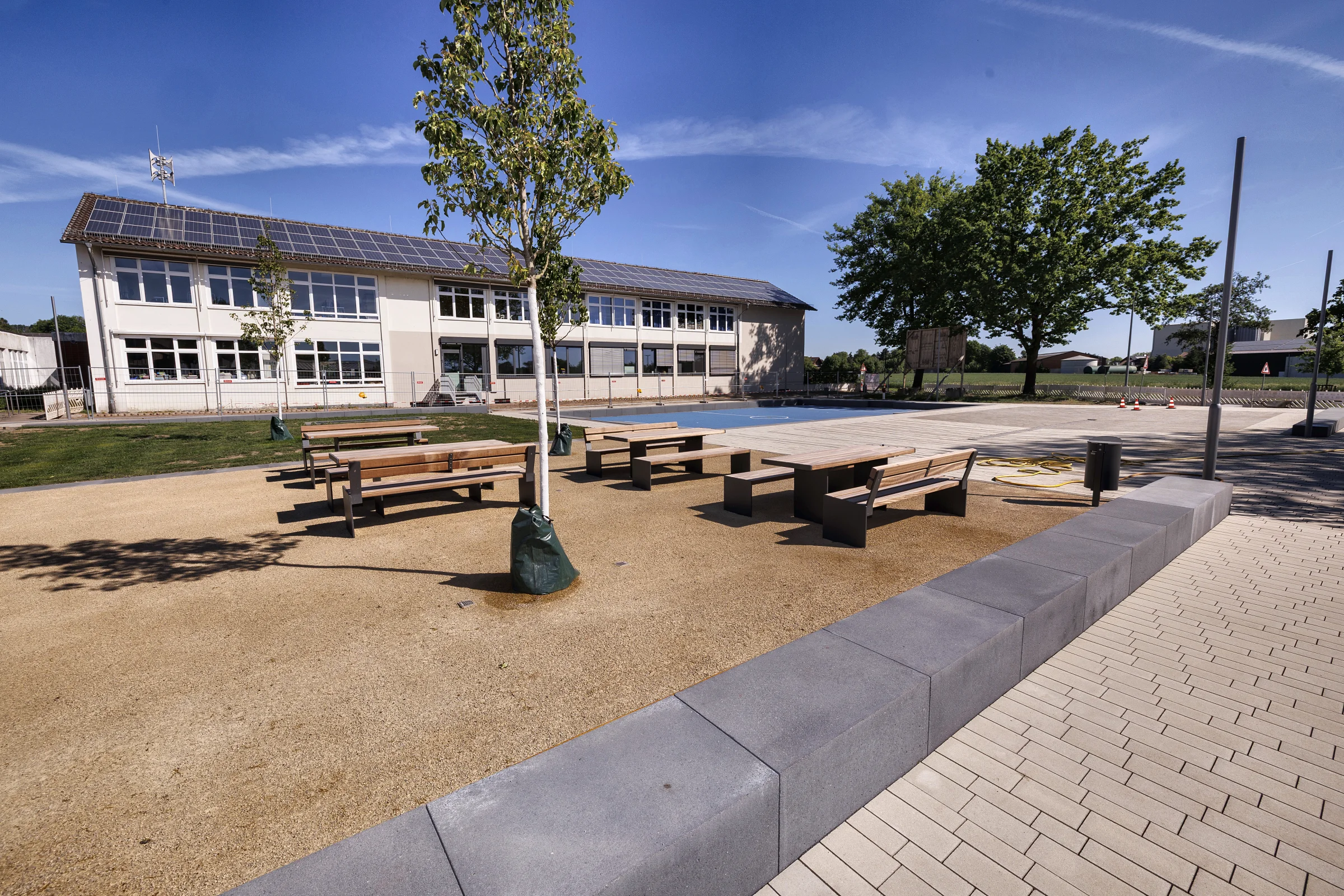 Außenlernbereich mit Sitzgruppen unter Bäumen als grünes Klassenzimmer