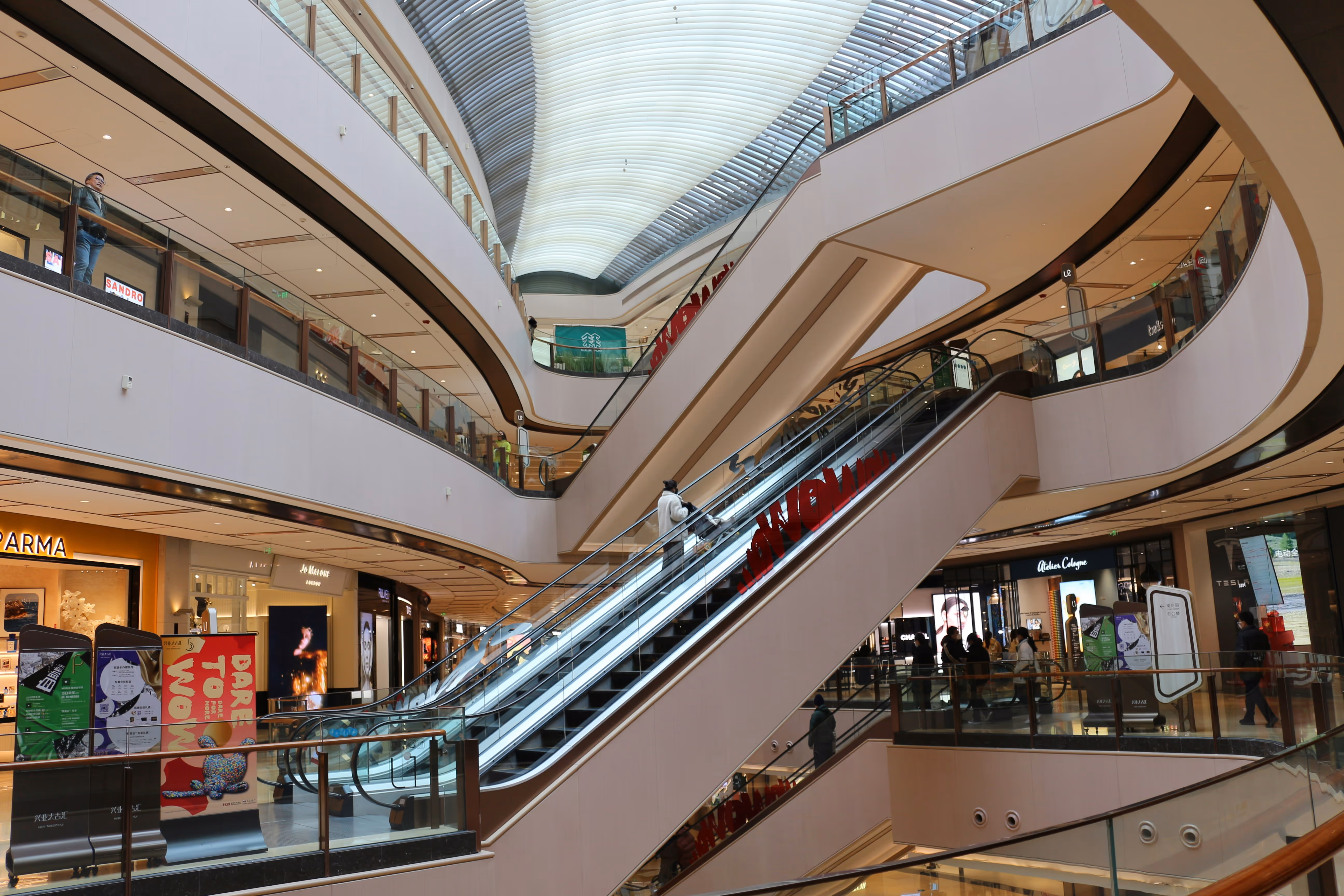 Interior de un centro comercial con escaleras mecánicas y gran afluencia de público, donde Brandtrack se encarga de la gestión centralizada de la música de fondo en los espacios compartidos y las zonas comunes
