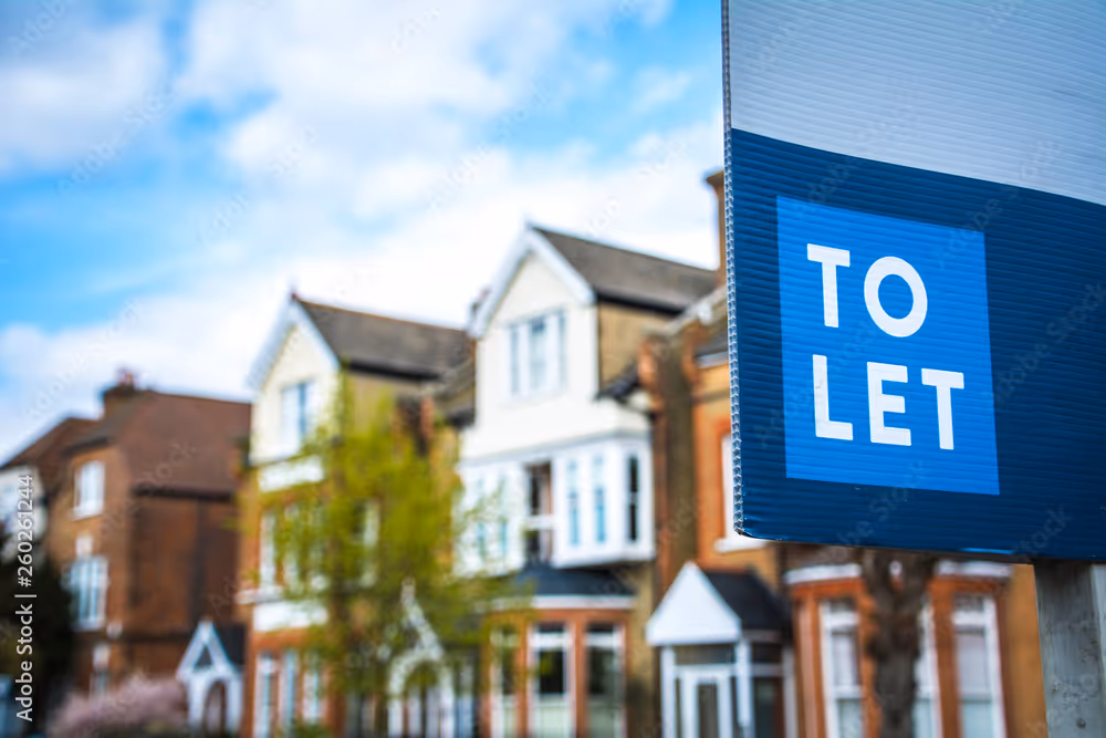 A "To Let" sign in front of a row of houses.