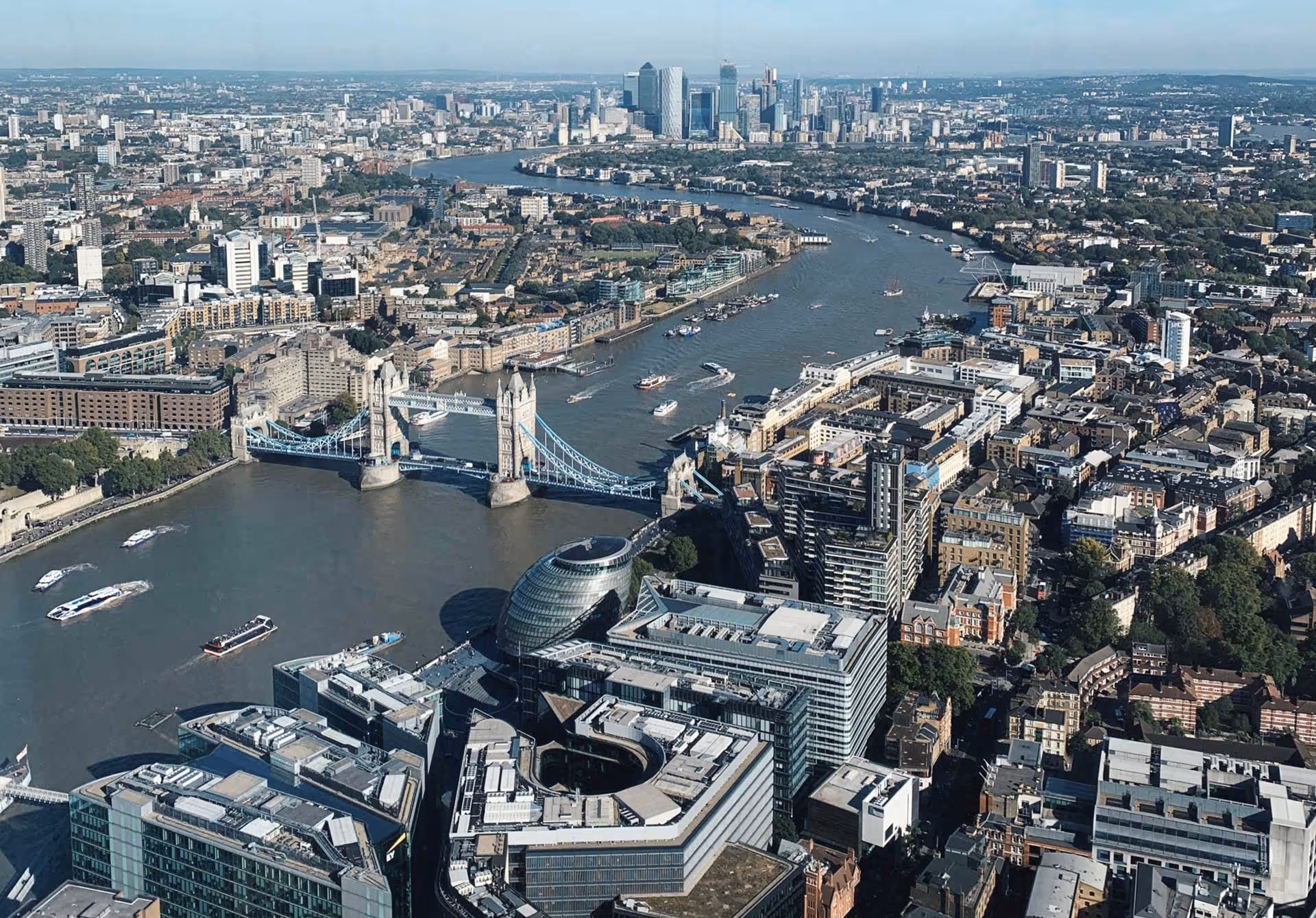 View of London with the Tower Bridge spanning the River Thames, city buildings in the background.