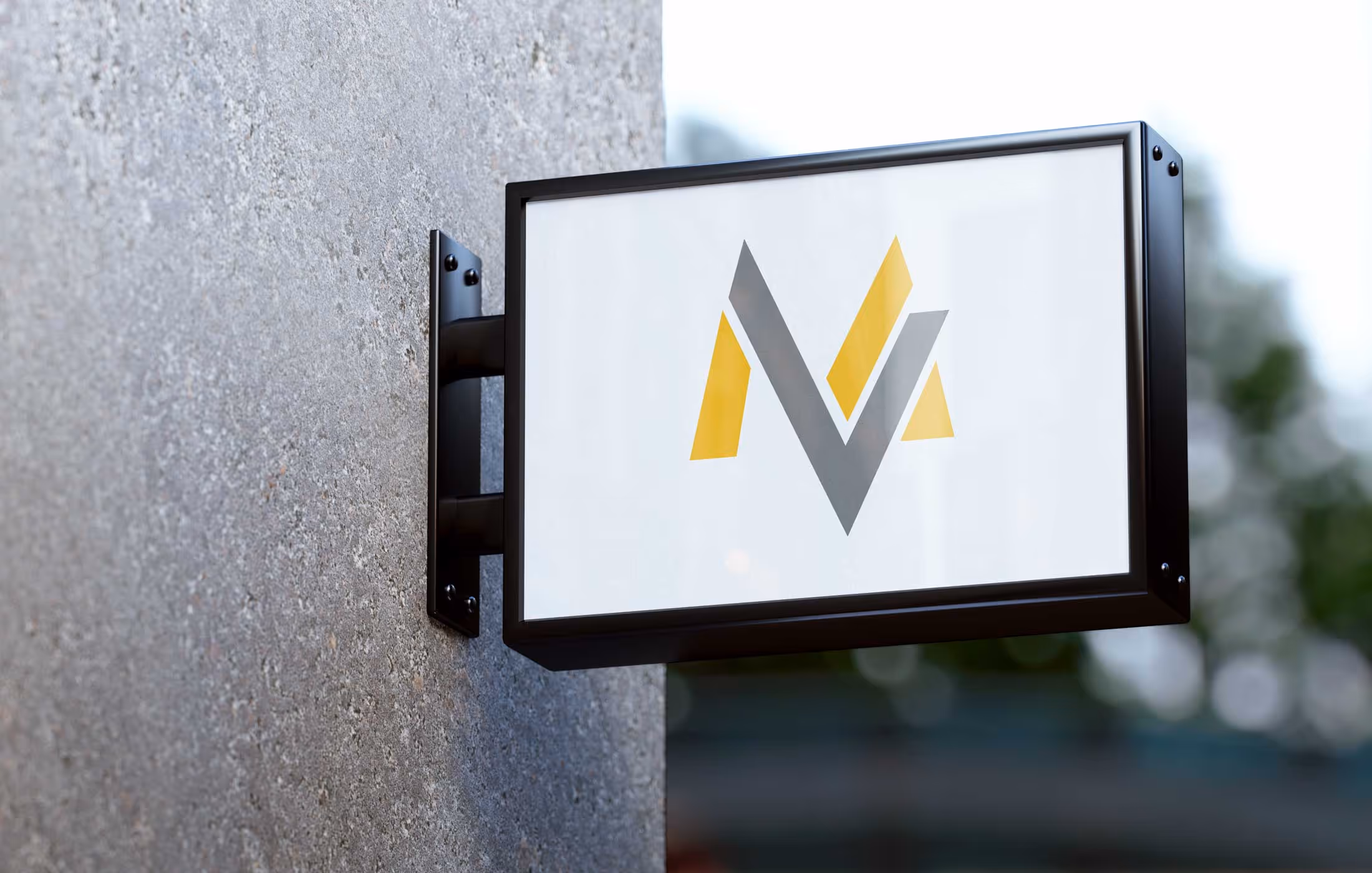 Wall-mounted sign displaying a stylized "M" with yellow and gray segments.