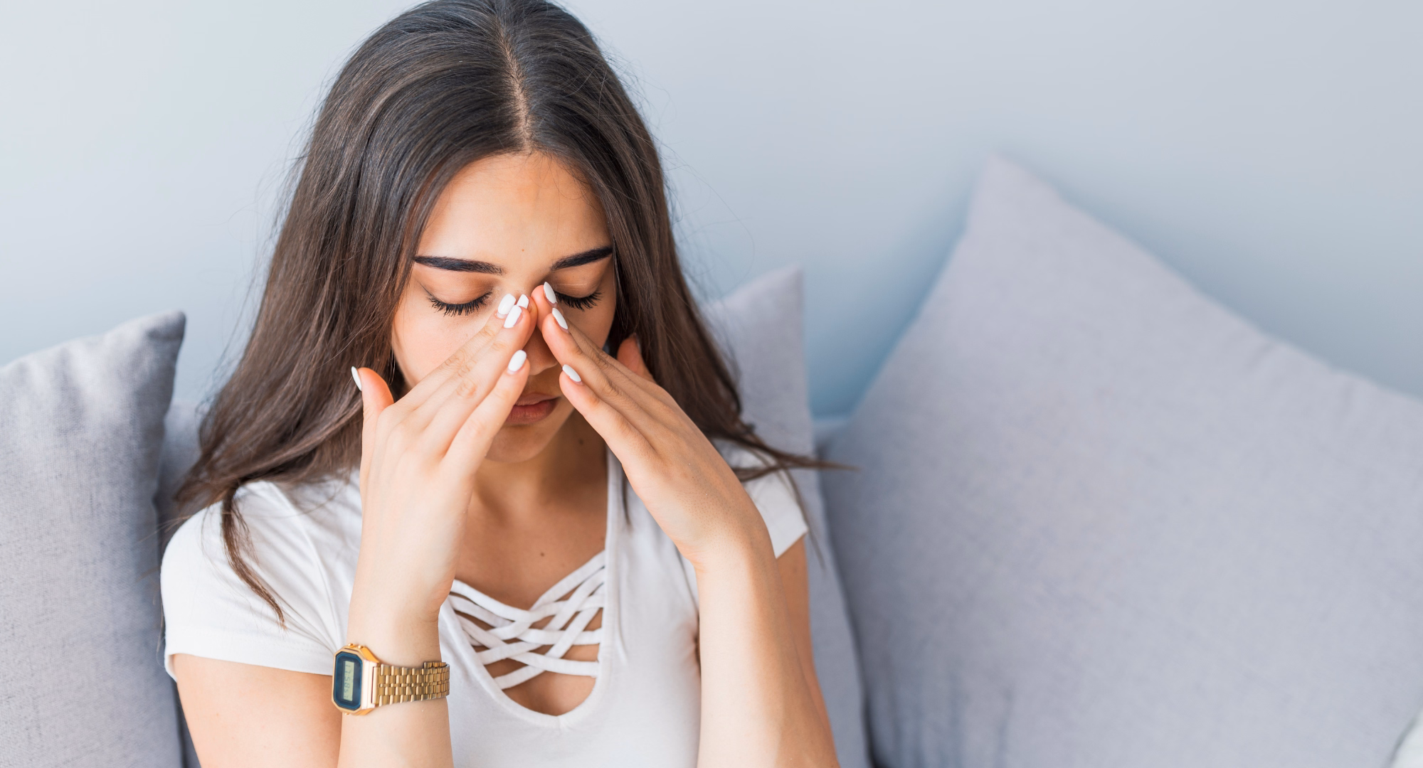 Žena sjedi na krevetu s rukama na nosu koji je boli jer ima sinusitis