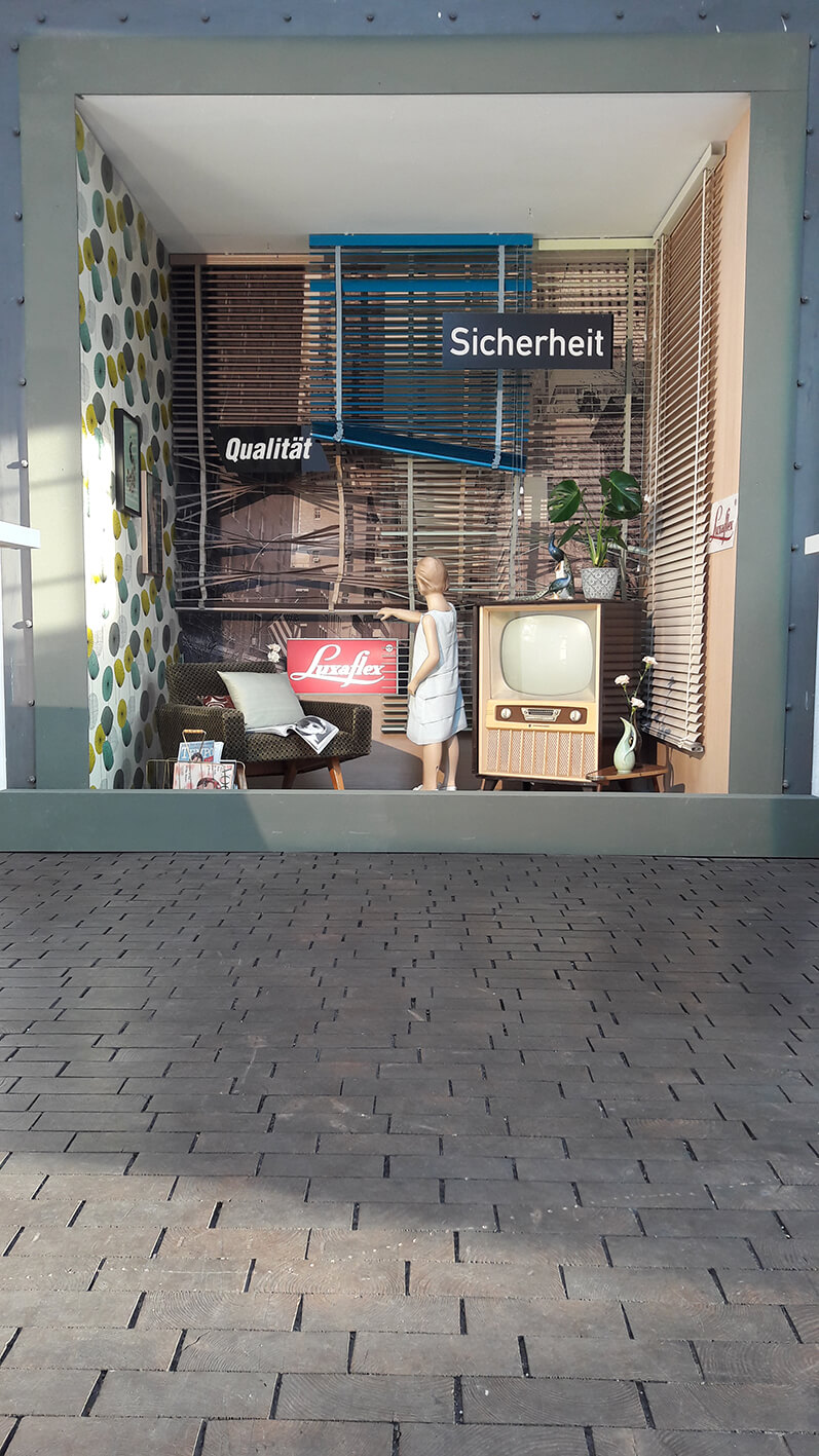 Street art featuring a mannequin and old window blinds.