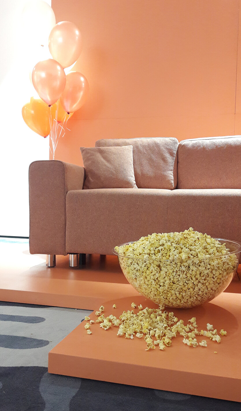 A huge popcorn ball in front of a pink couch.