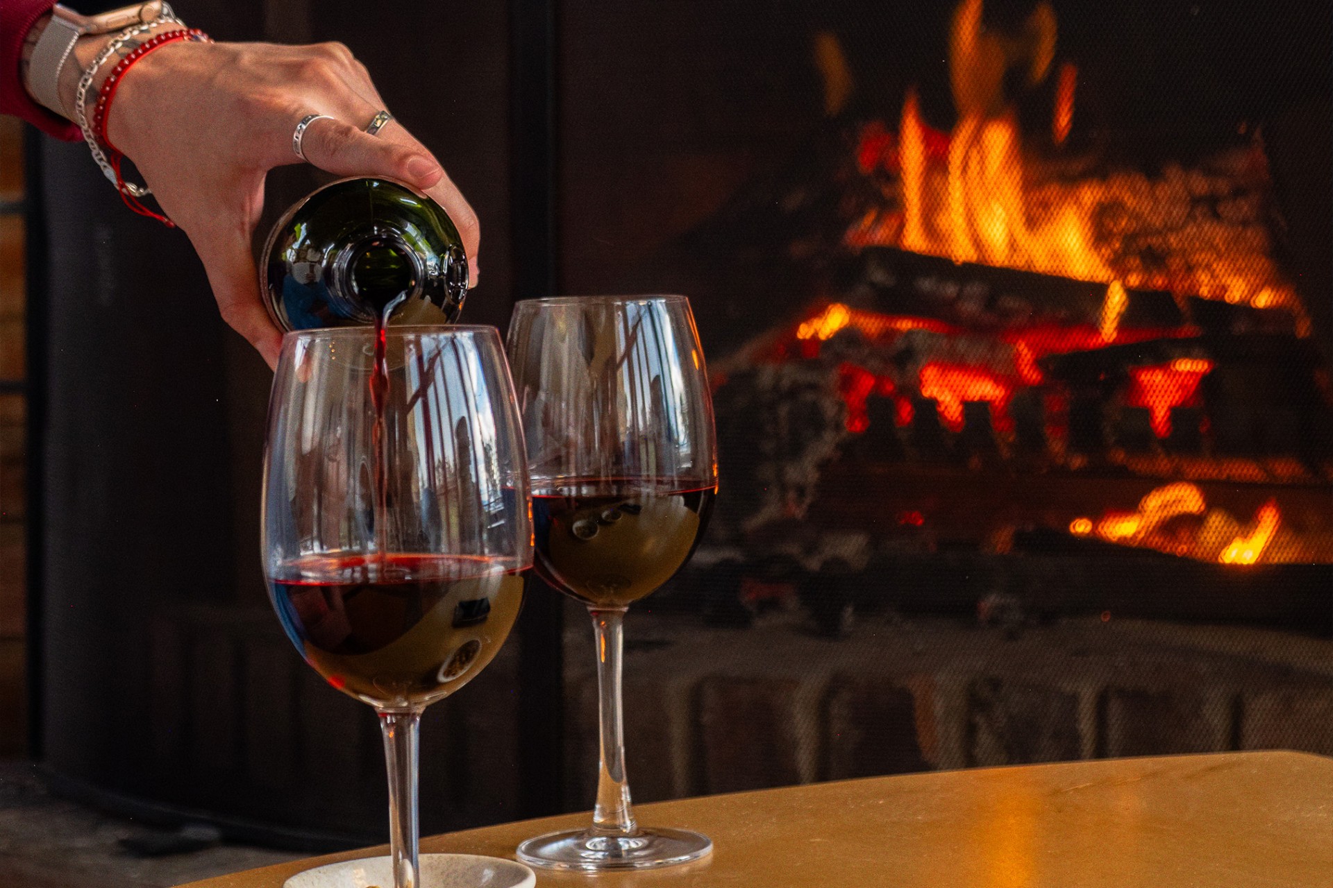 Copas de vino junto a una chimenea encendida en Hotel 1572 El Origen, creando un ambiente cálido y acogedor para una experiencia de descanso en Villa de Leyva.