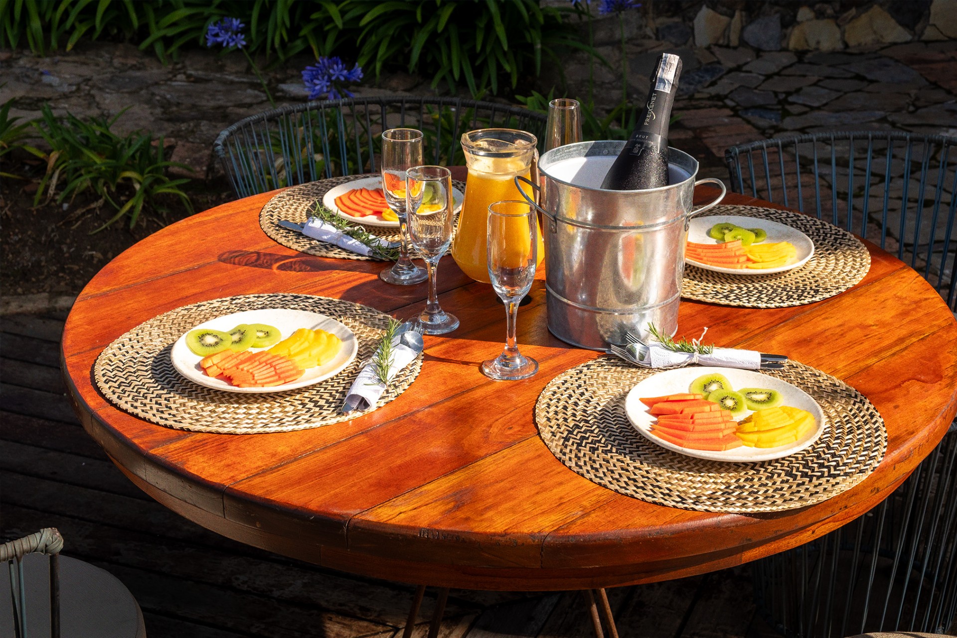 Mesa de desayuno al aire libre en Hotel 1572 El Origen con frutas frescas, bebidas y ambiente natural, ideal para compartir una experiencia de descanso en Villa de Leyva.”