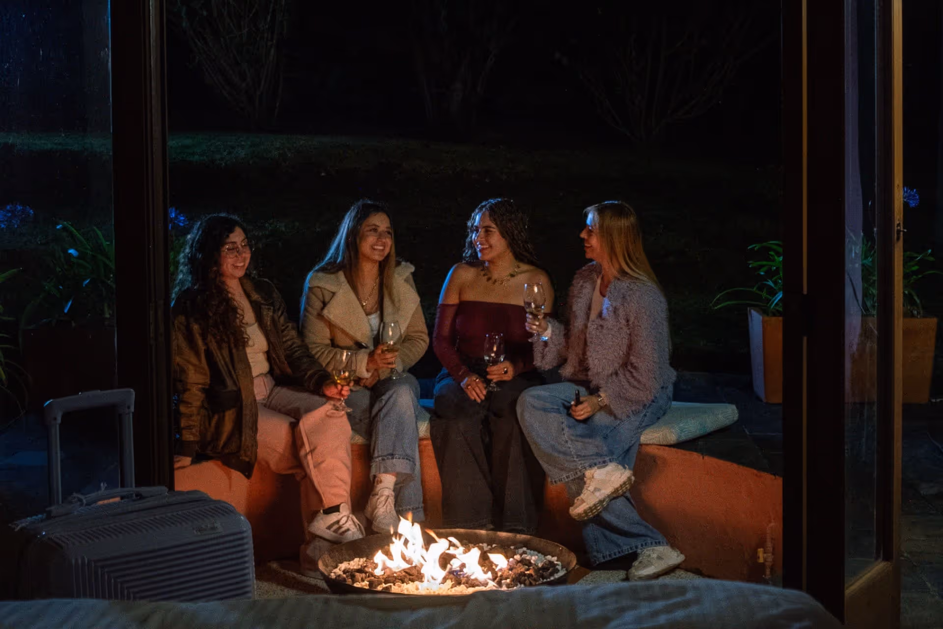 Grupo de amigas compartiendo alrededor de una fogata en Hotel 1572 El Origen en Villa de Leyva, disfrutando una experiencia acogedora de descanso y conexión.”