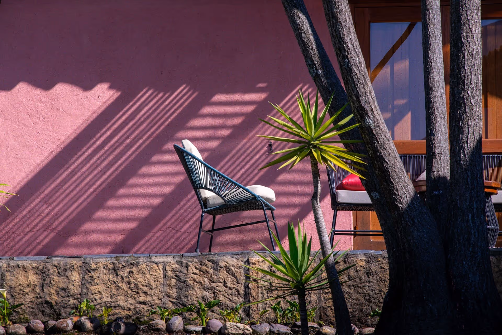 Espacio exterior del Hotel 1572 El Origen en Villa de Leyva con arquitectura rosada, luz natural, vegetación y ambiente tranquilo para descansar y desconectarse.