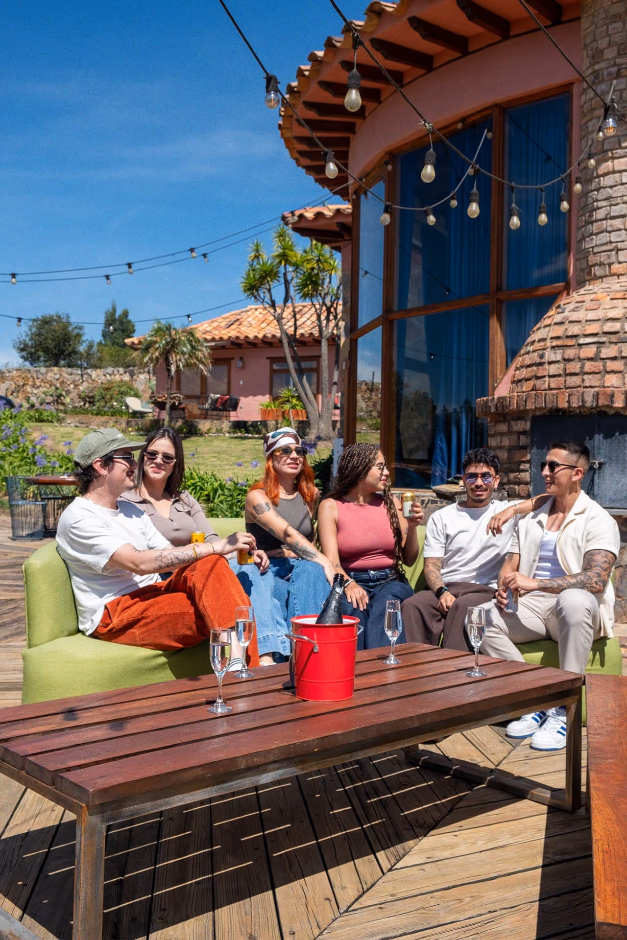 Grupo de amigos disfrutando una tarde al aire libre en la terraza del Hotel 1572 El Origen en Villa de Leyva, rodeados de naturaleza, arquitectura rústica y ambiente relajado.