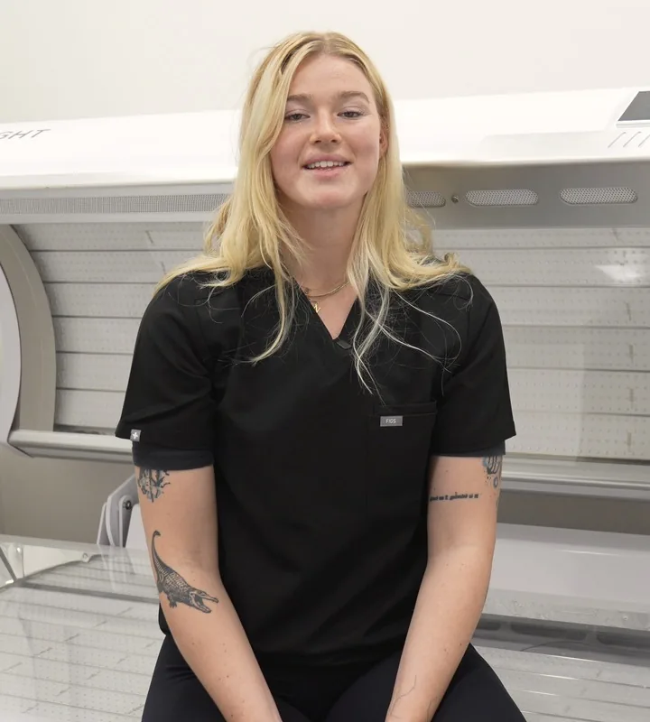 Natalie Crews, health consultant, sitting on the red light therapy bed at 8 West
