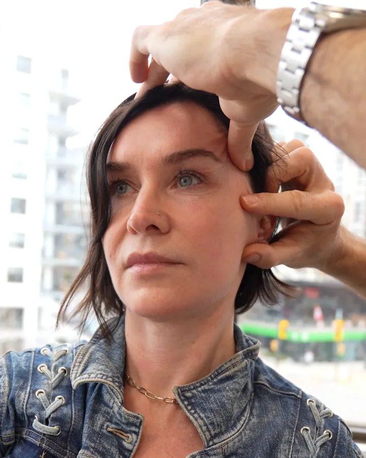 Dr. Buonassisi gently lifting a woman's brow and cheek during a facelift consultation