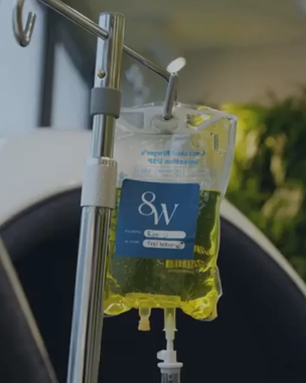 An IV bag with the 8 West label, hanging beside a lounge chair