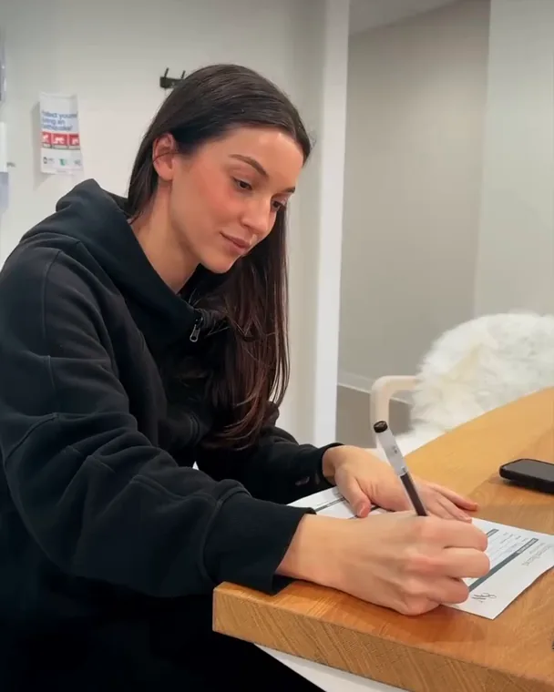 A client filling in a form at the front desk before her IV