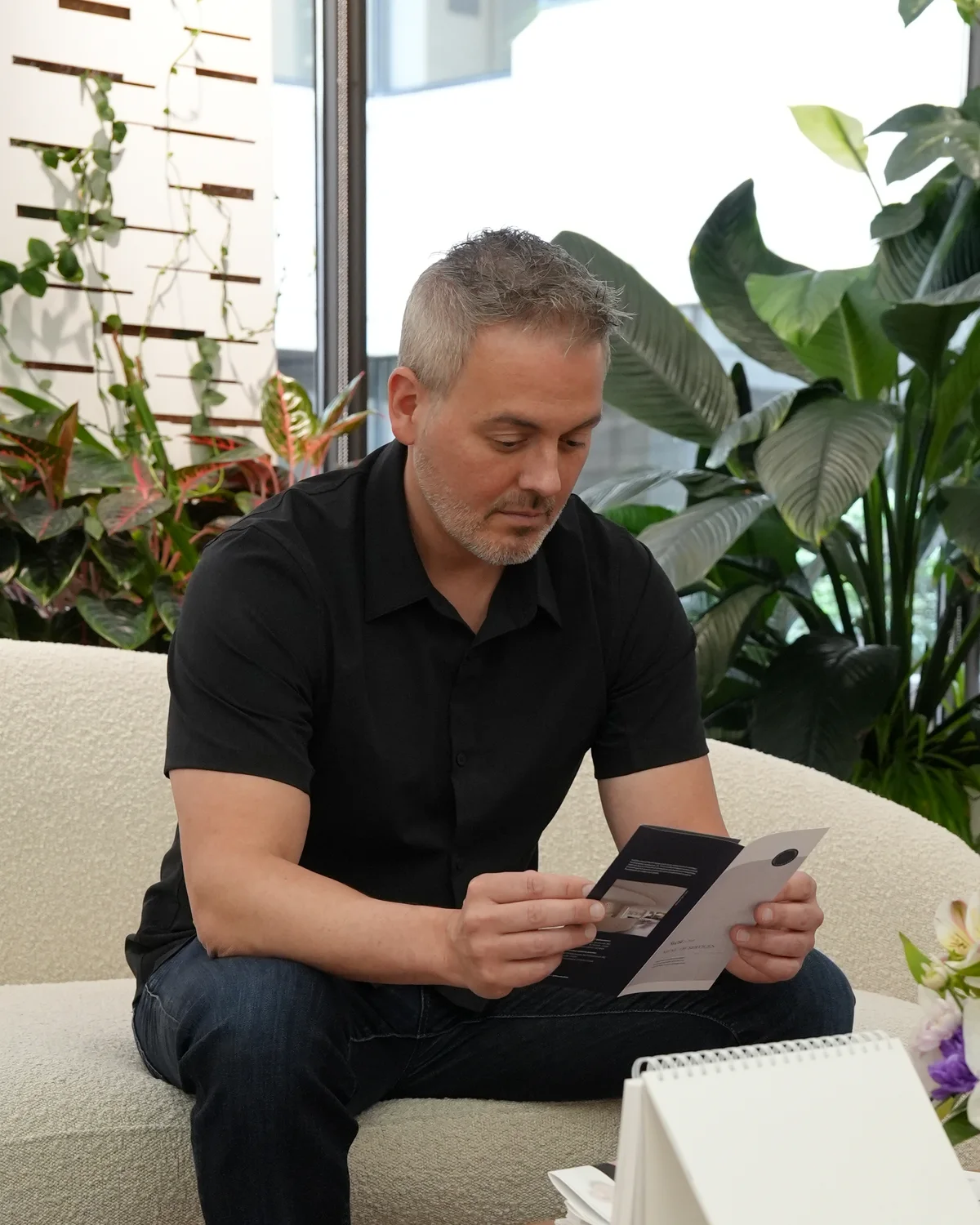 A man reading a brochure in the reception at 8 West Clinic