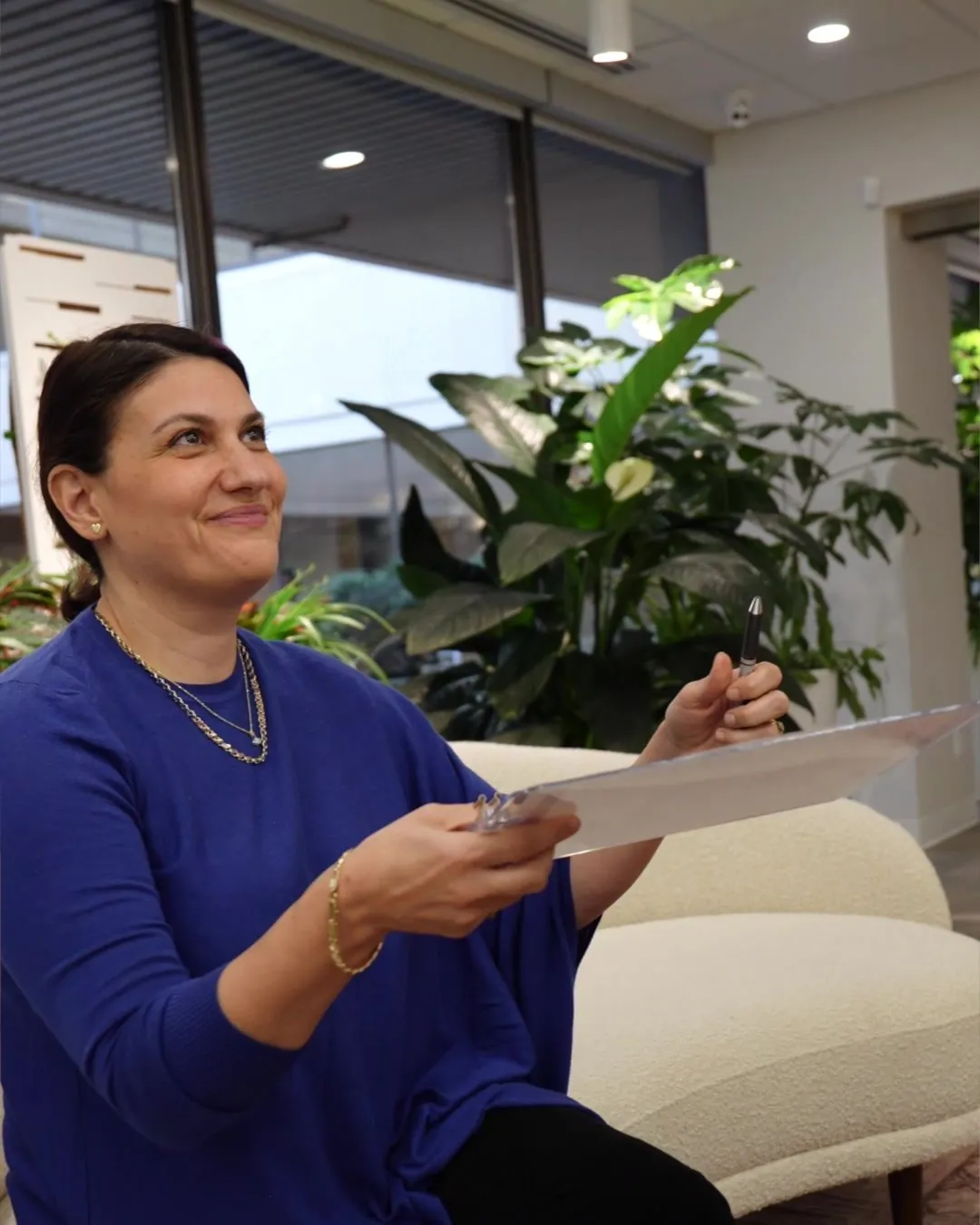A woman smiling as she reads her forms in the lounge at 8 West Clinic