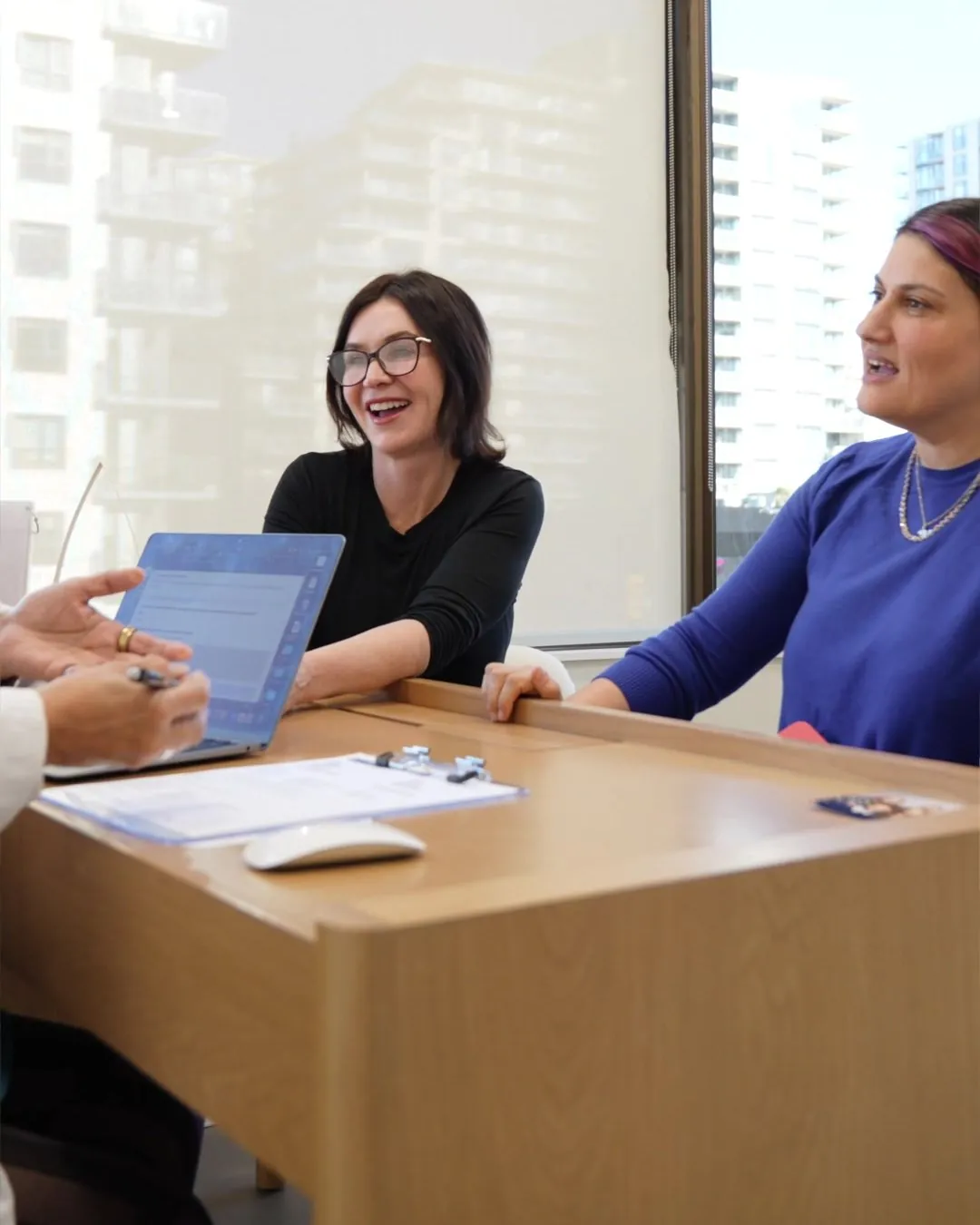 A patient laughing with a member of our team at a desk at 8 West Clinic