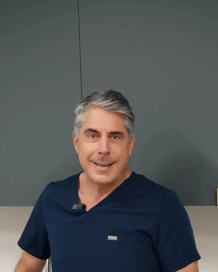 Dr. Buonassisi in surgical scrubs, answering a question about natural rhinoplasty