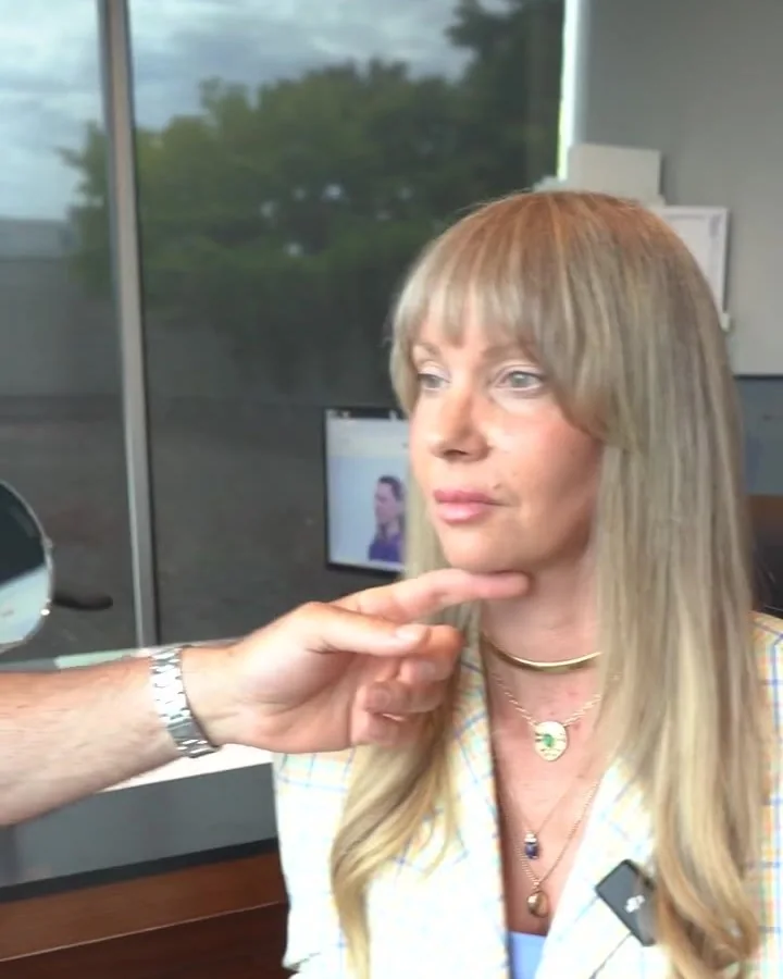 Dr. Buonassisi checking a woman's jawline at her two-month follow-up