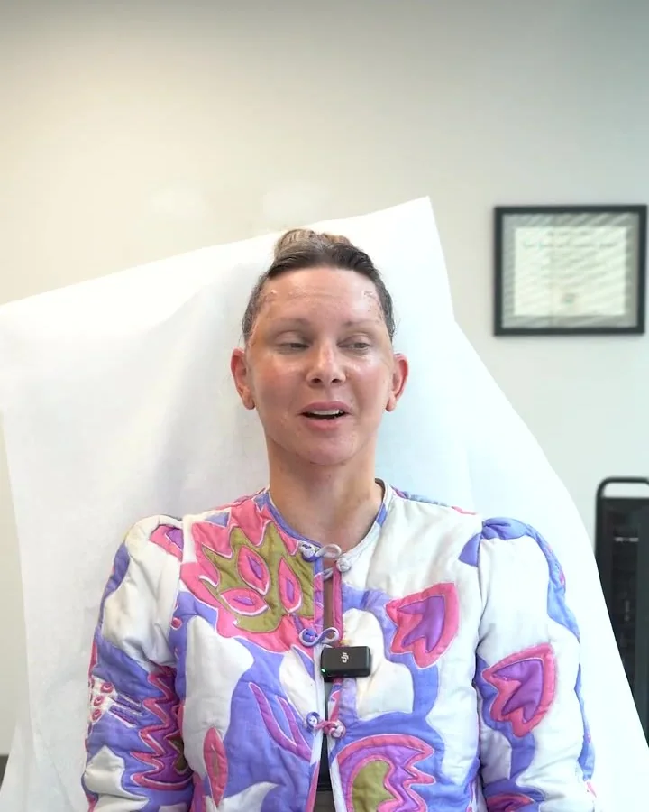 A woman seated in a consultation room a week after her facelift