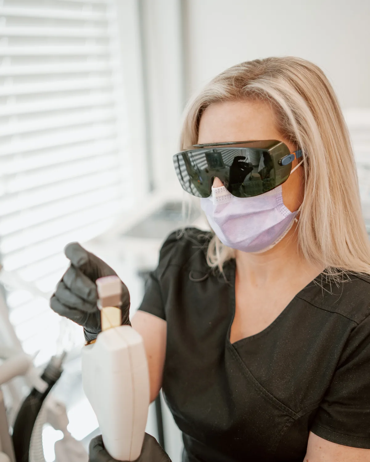 Suzanne Power, senior medical aesthetician, in laser safety glasses holding a BBL handpiece