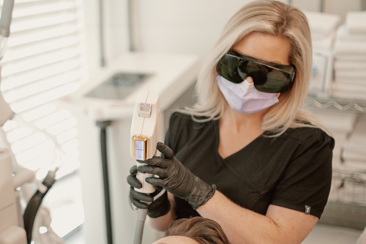 Suzanne, medical aesthetician, in laser safety glasses holding a BBL handpiece at 8 West Clinic
