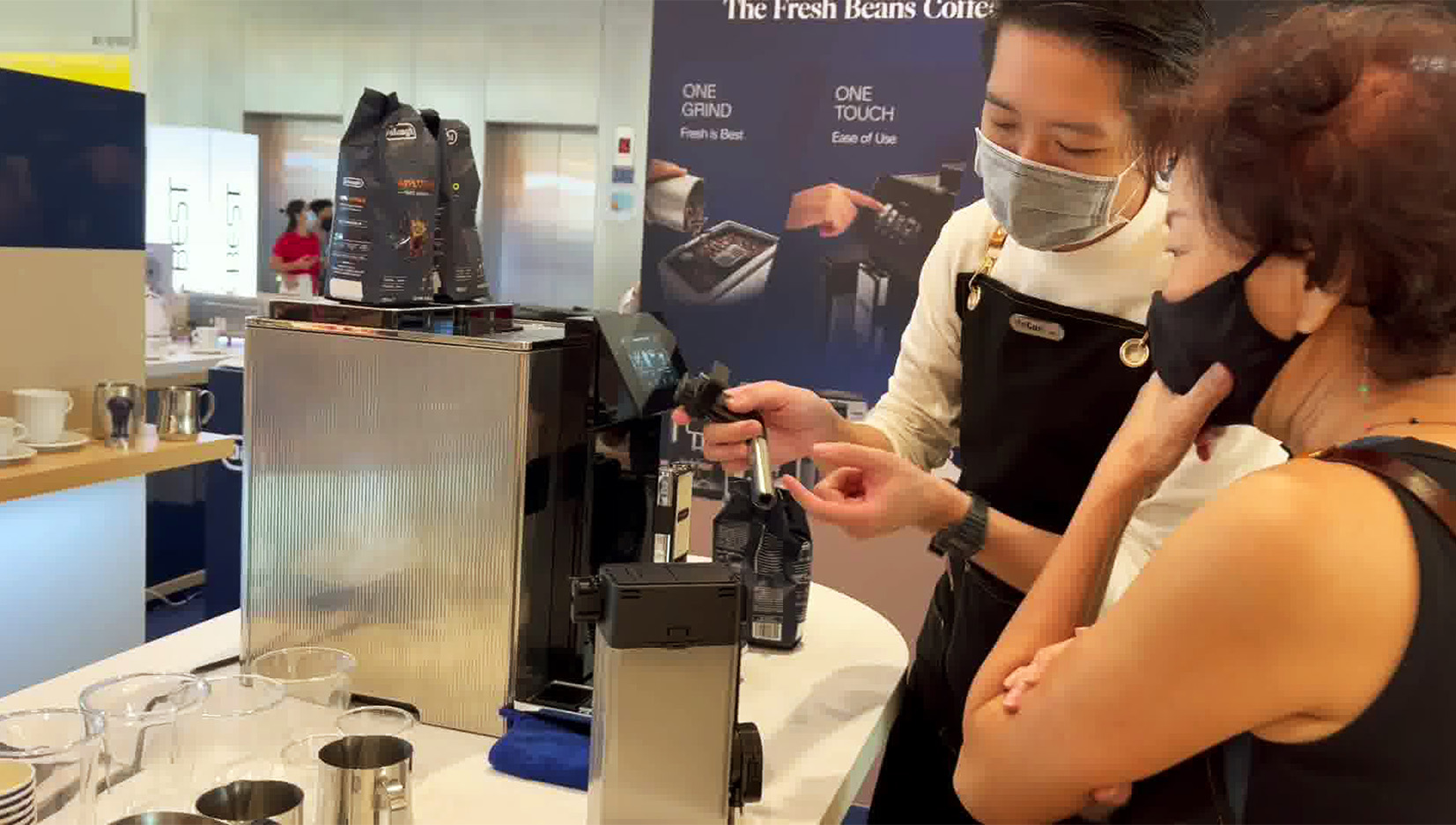 A brand ambassador explaining parts of the coffee machine that was on the counter to a customer